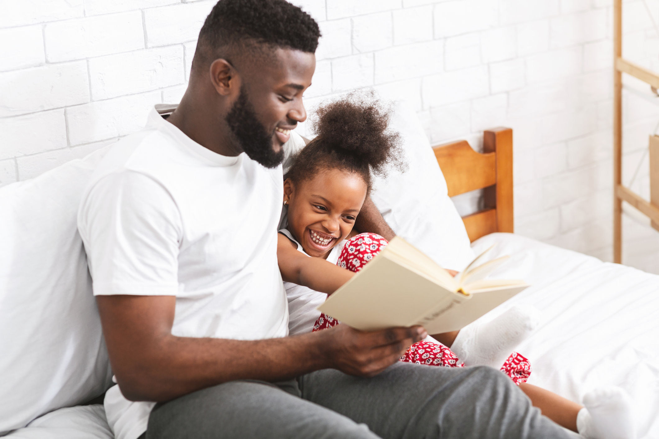 Loving african american dad reading fairy tales to his little daughter