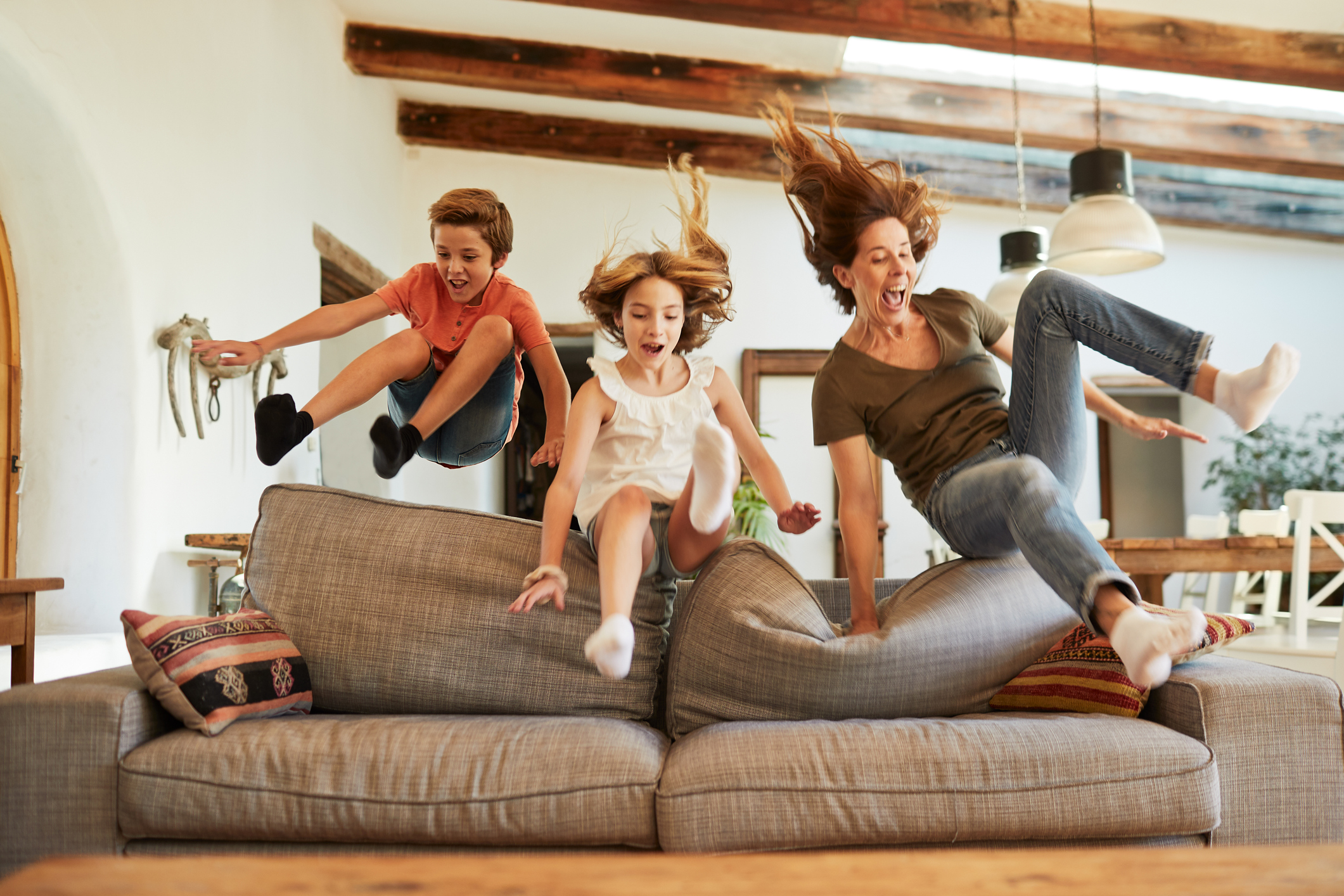 Race for the best spot on the sofa. Mother and children jumping.