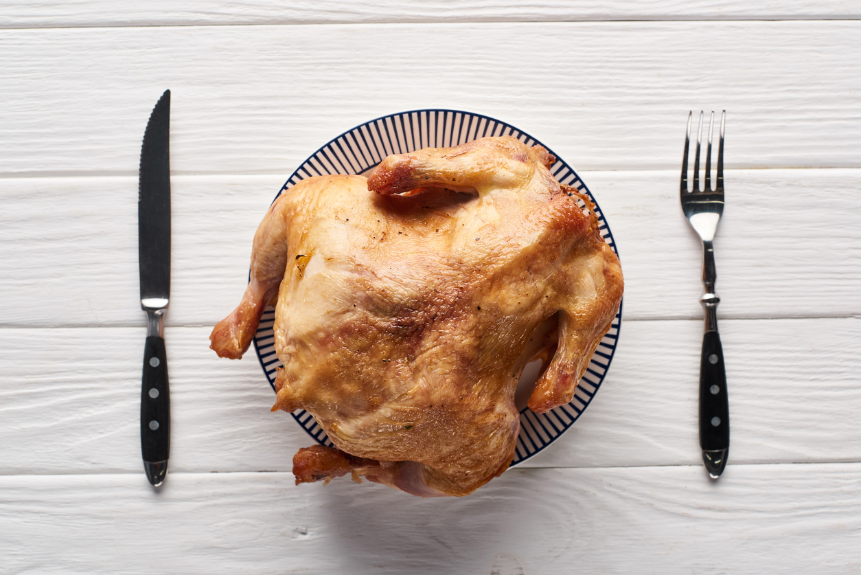 top view of turkey served at white wooden table with cutlery for Thanksgiving dinner