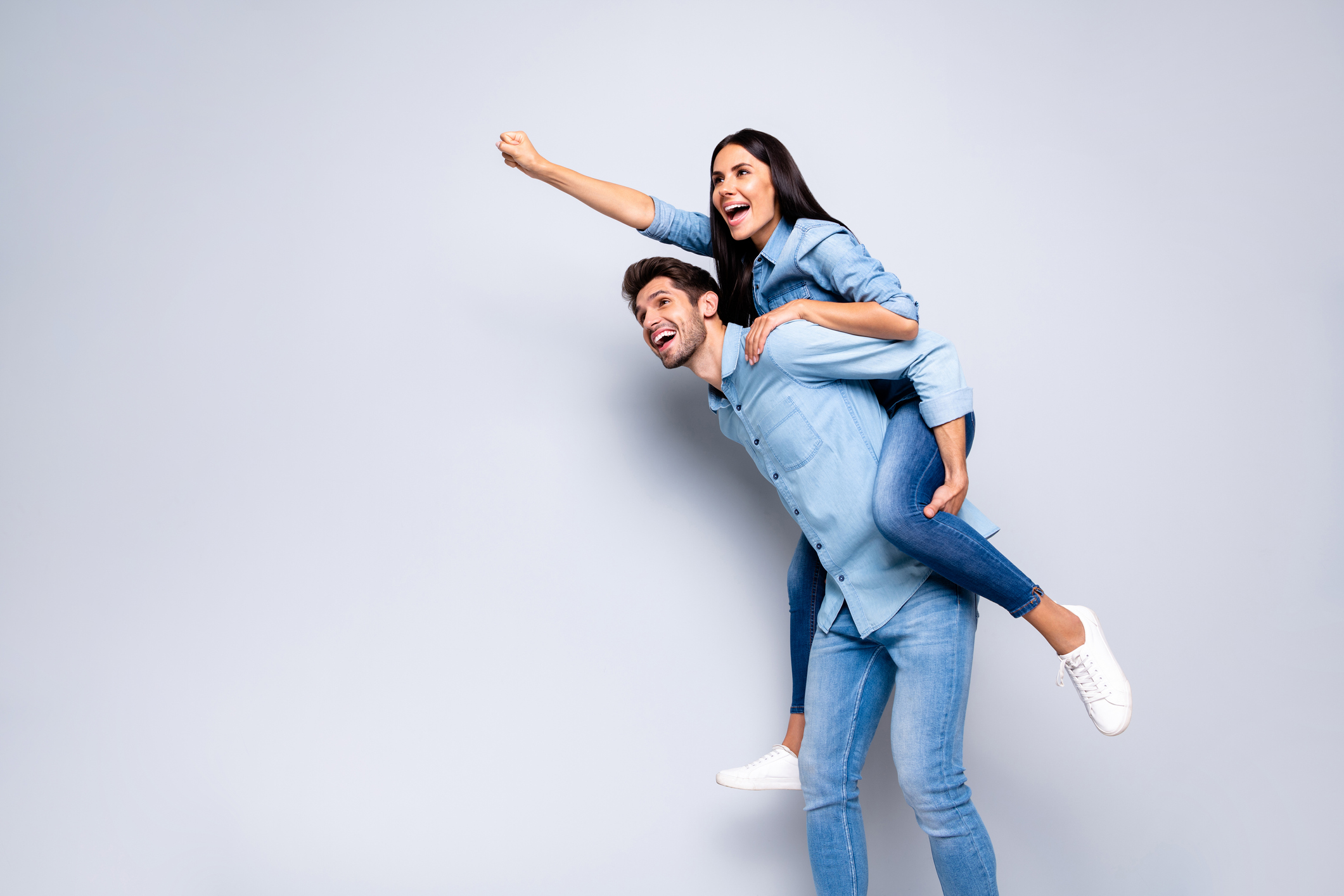 Photo of cool pair guy holding lady piggyback pretending flight up using super powers wear casual jeans clothes isolated grey color background