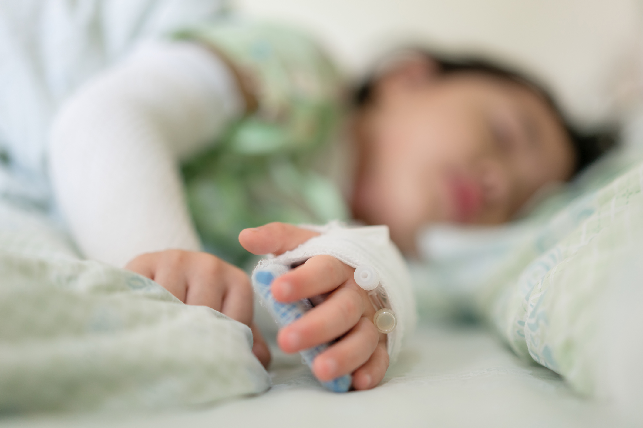 Little asian girl was lying ill in bed at the hospital, Close-up children hand intravenous treat with the brine at hospital.