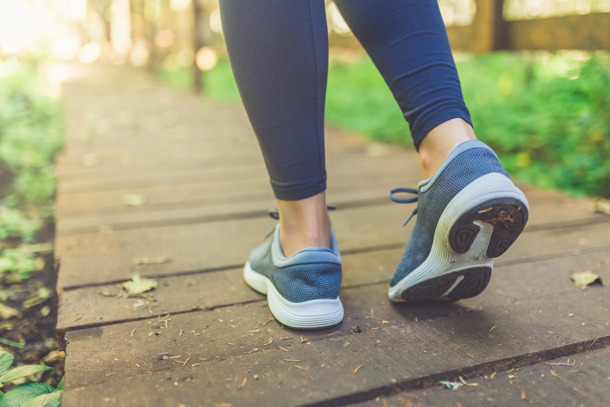 Woman runner feet walking in nature. Close up on shoes. Healthy lifestyle fitness concept.