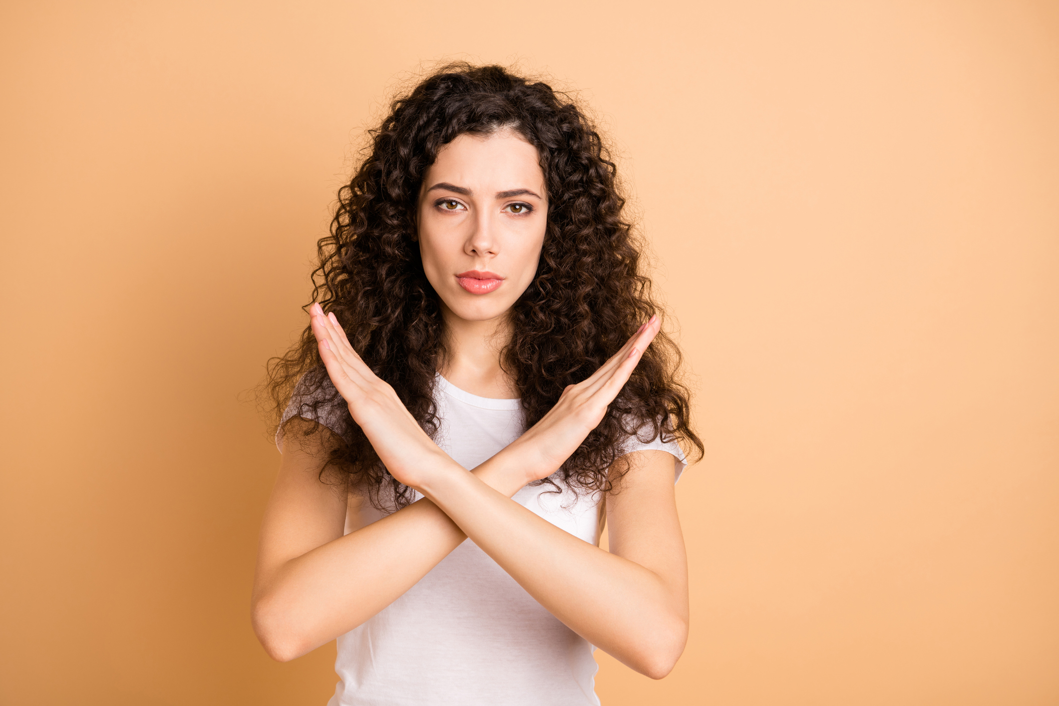 Photo of trendy serious brunette casual confident girlfriend showing you hands crossed restricting your access isolated over beige pastel color background