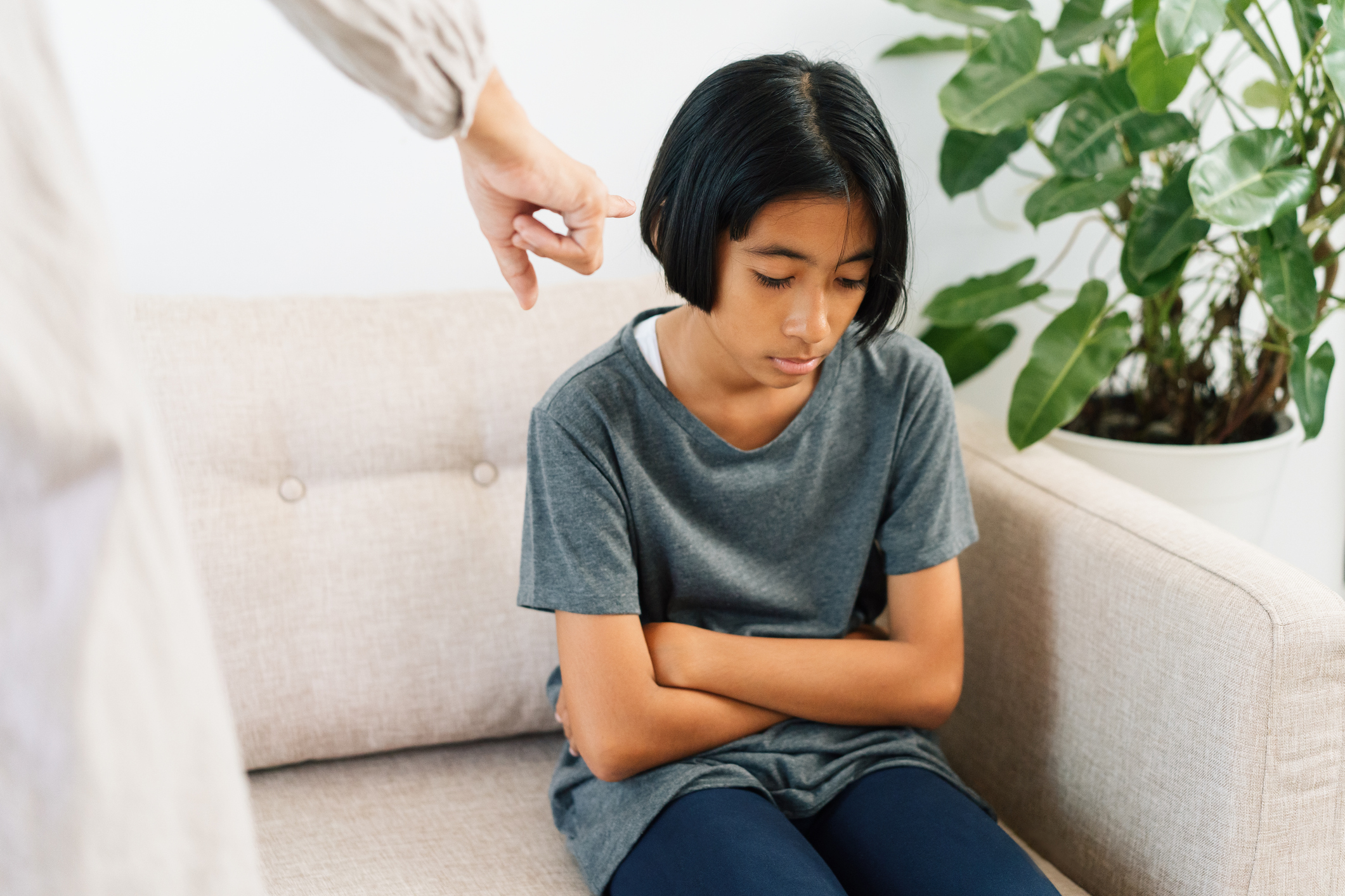 Asian mother is angry and scold her daughter while sitting on the sofa because of bad behavior. The concept of domestic violence.