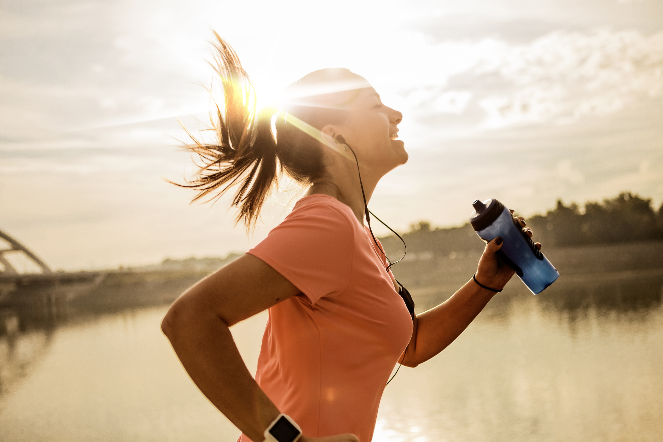 Young woman running against morning sun