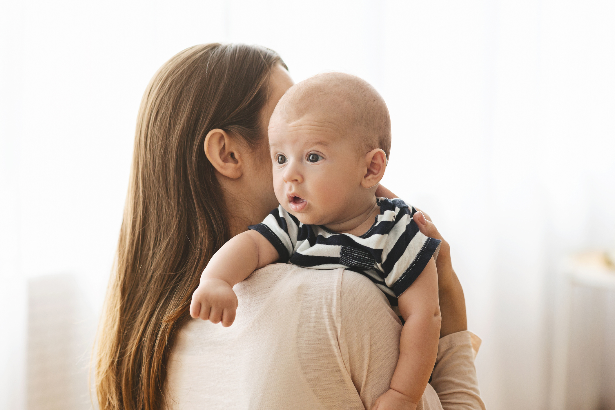 Mother patting adorable baby on back after breasfeeding