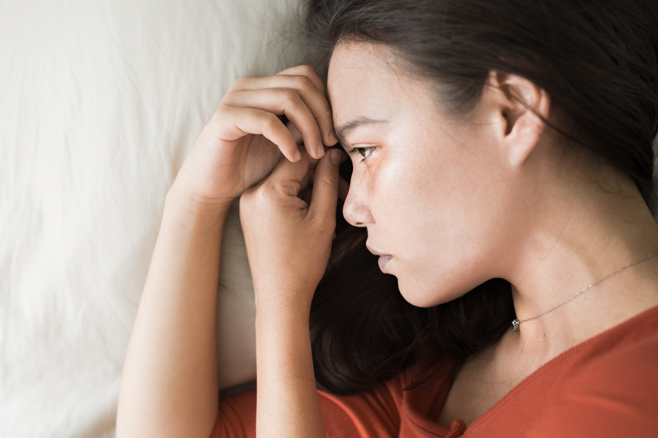 A sad depressed woman lying in bed.