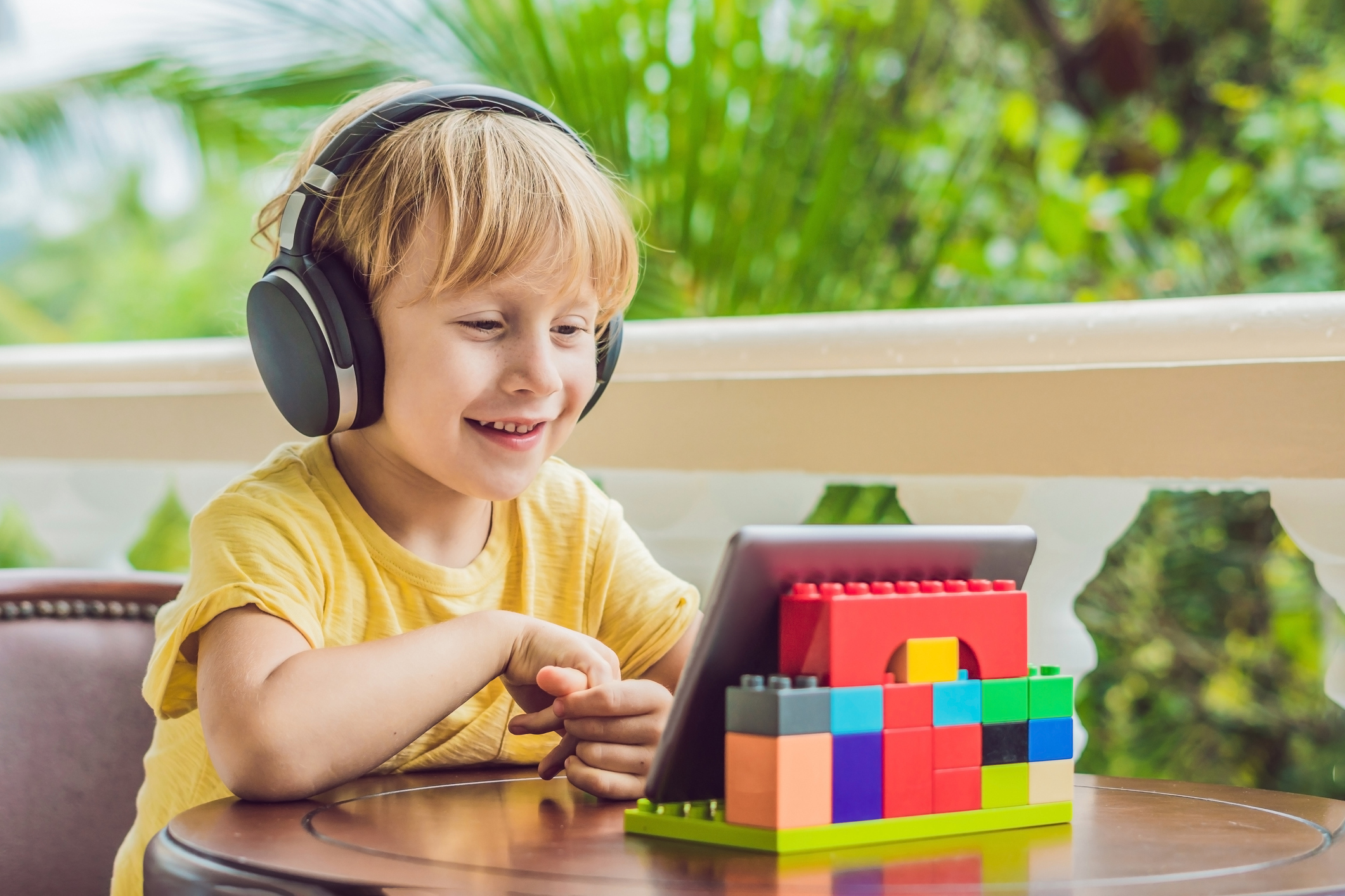 boy in tropics talking with friends and family on video call using a tablet and wireless headphones