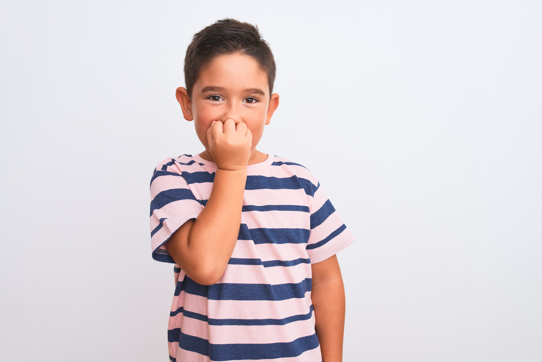 Beautiful kid boy wearing casual striped t-shirt standing over isolated white background looking stressed and nervous with hands on mouth biting nails. Anxiety problem.