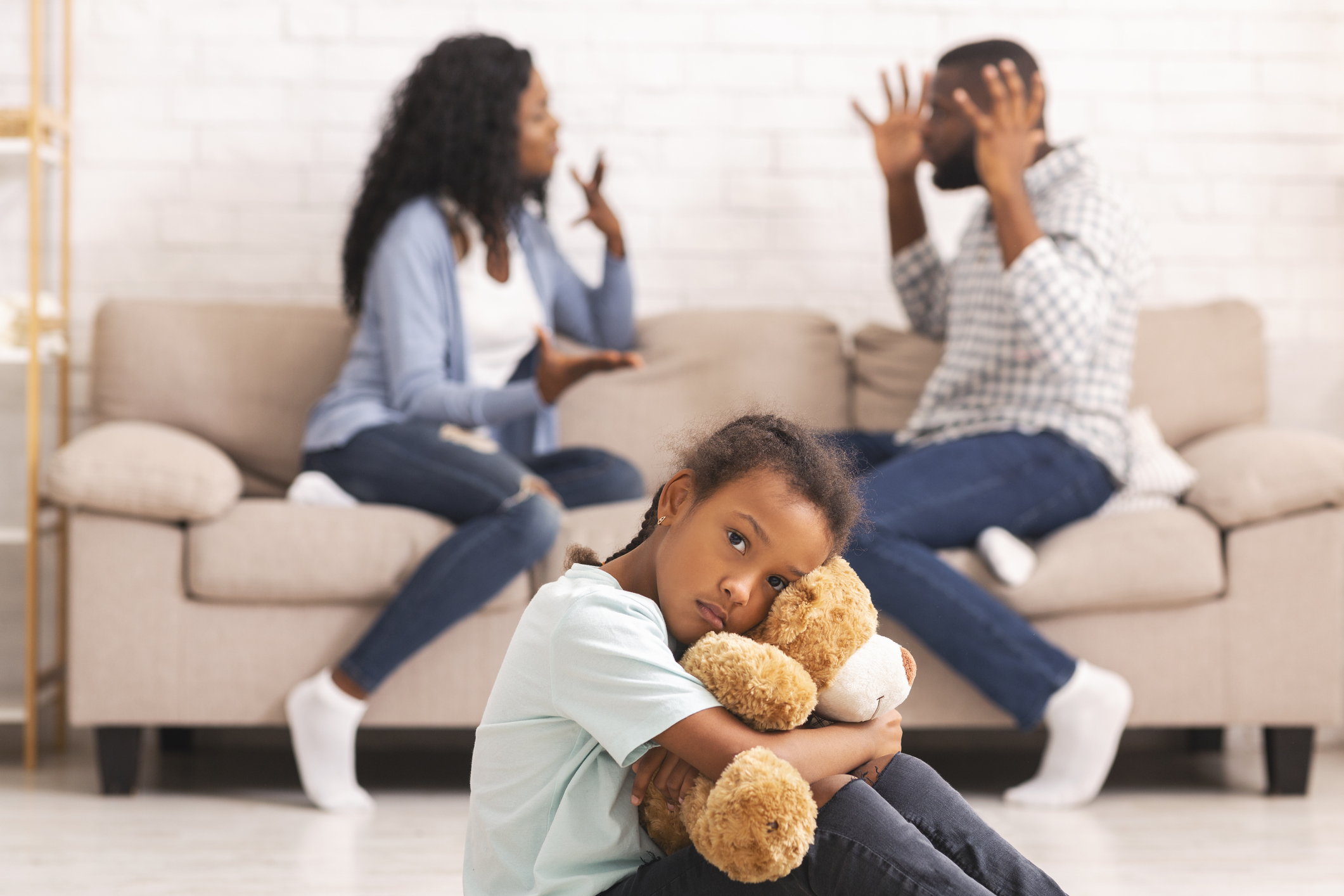 Child suffering from parents quarrels, sitting and cuddling teddy bear