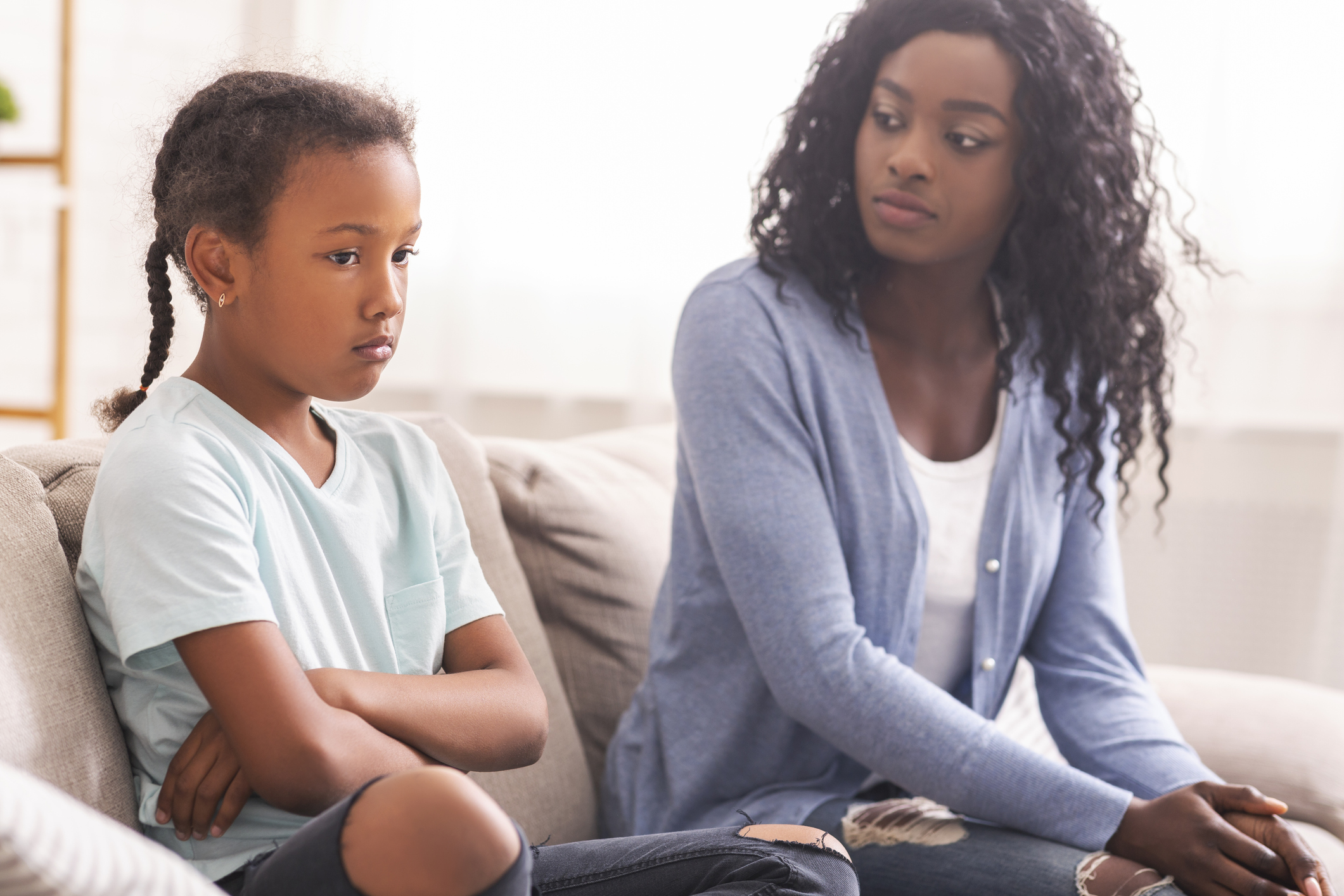 Disappointed black mother looking at her little daughter with reproach