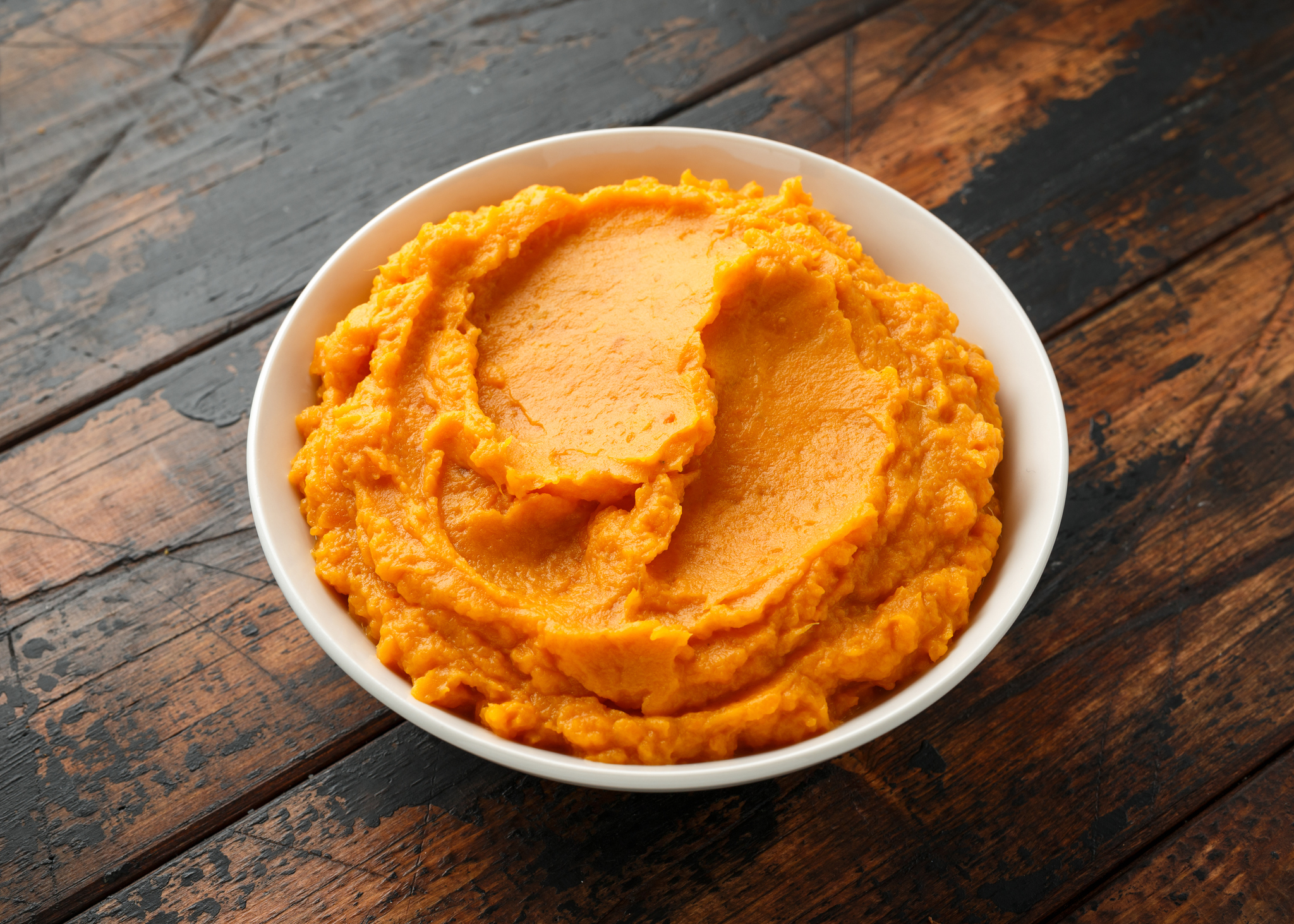 Mashed Sweet Potatoes in white bowl on wooden rustic table. Healthy food