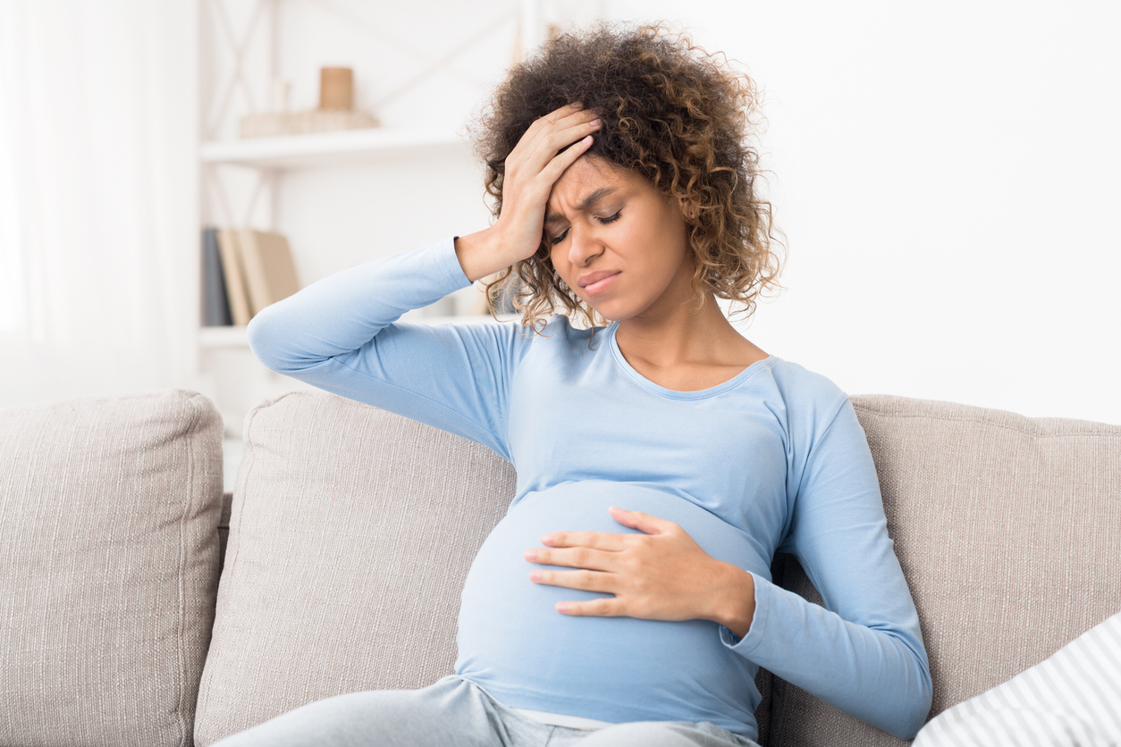 Pregnant afro girl suffering from headache at home