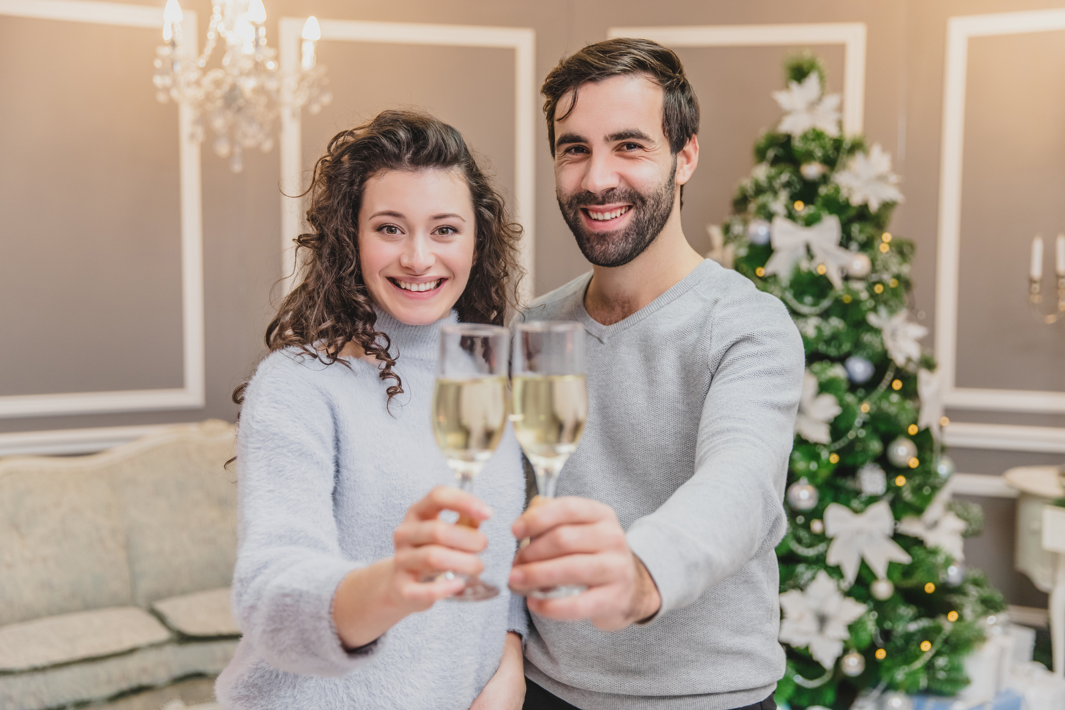 Toasting with champagne glasses against holiday lights and christmas tree.