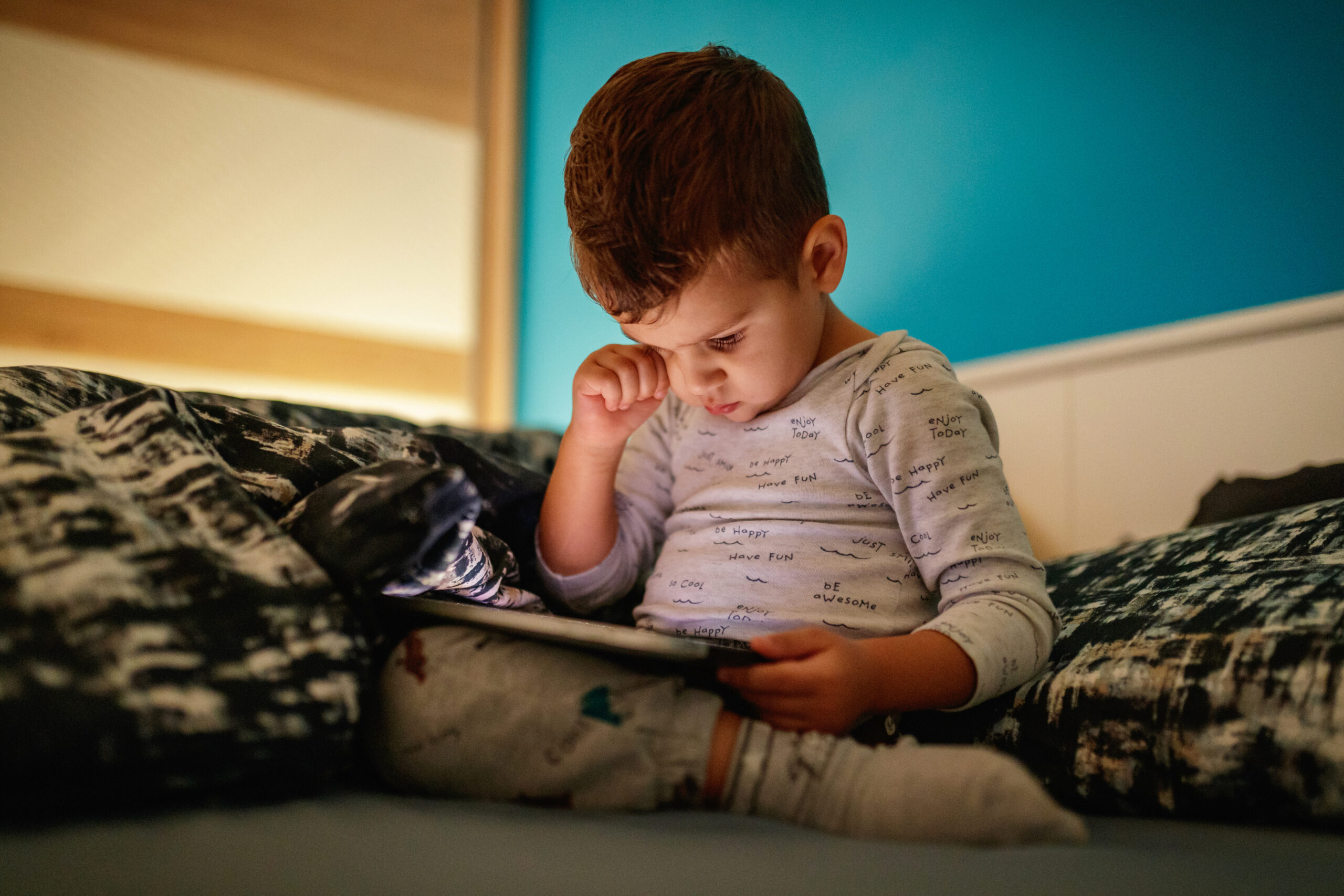 Sleepy boy uses digital tablet in bed