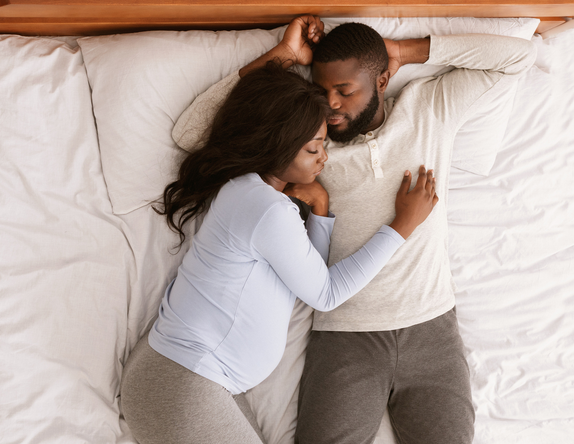 Lovely pregnant couple sleeping together at home