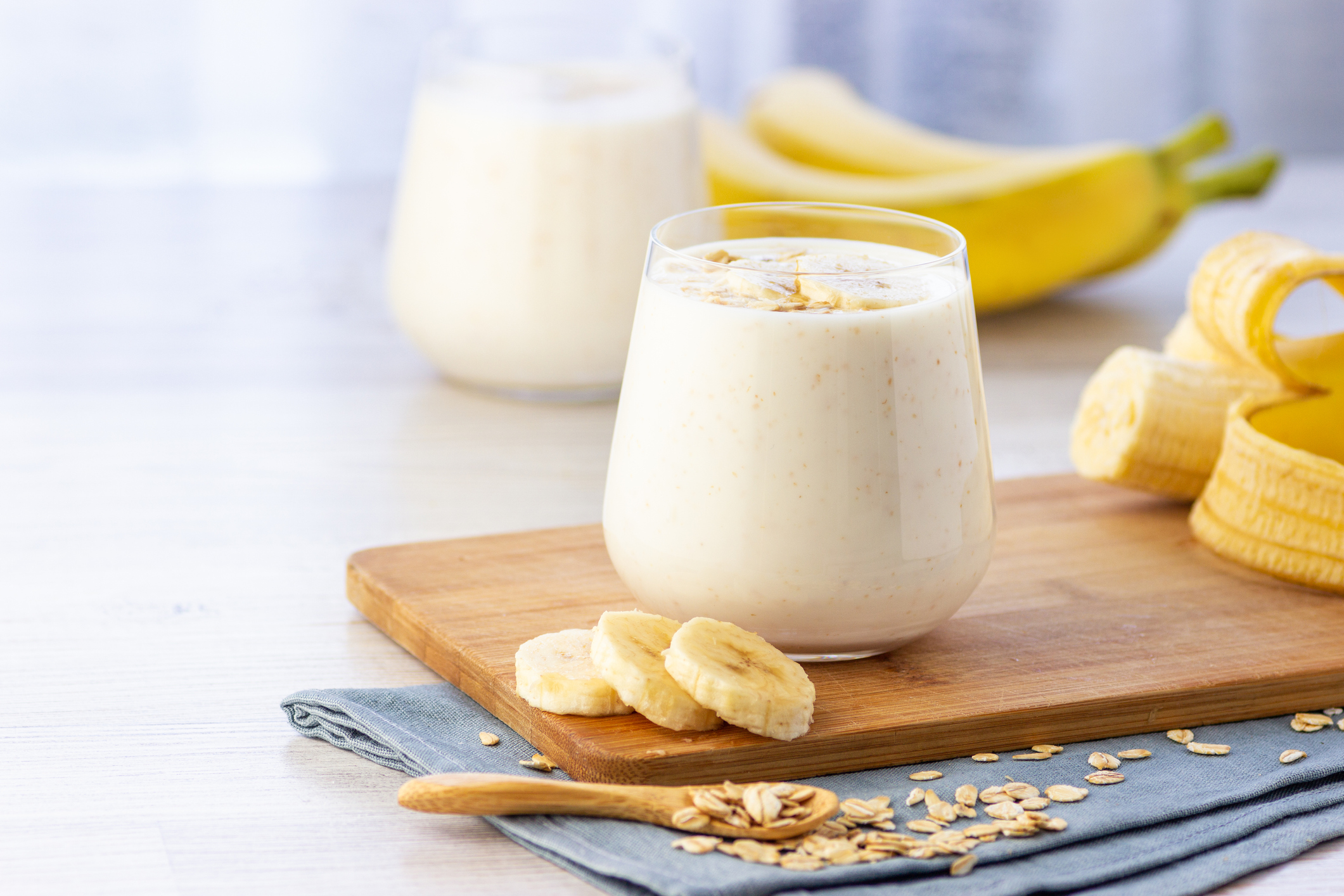 Vegan banana and oatmeal smoothie in glass jar on the light background.