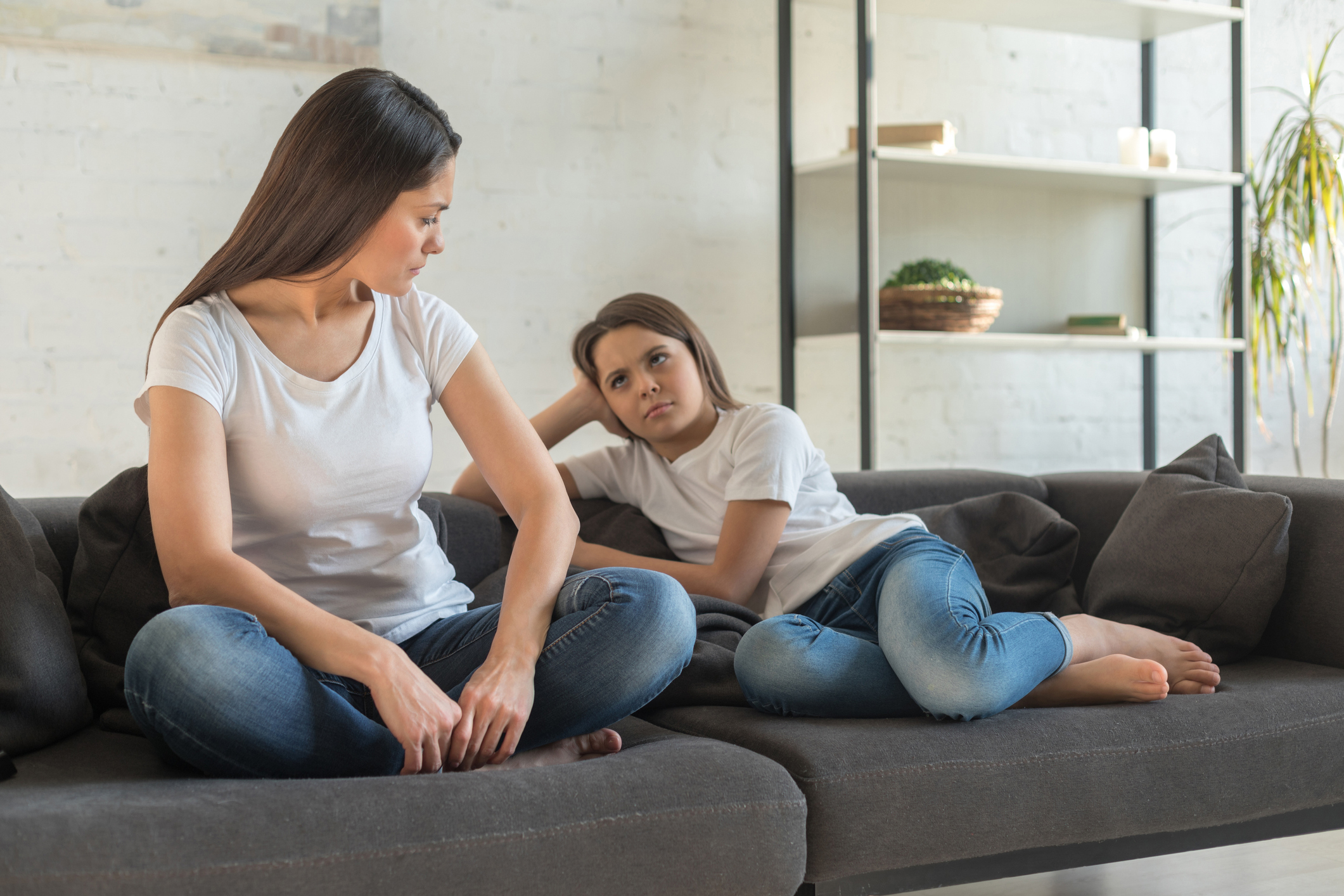 Child and mother sitting on sofa not talking