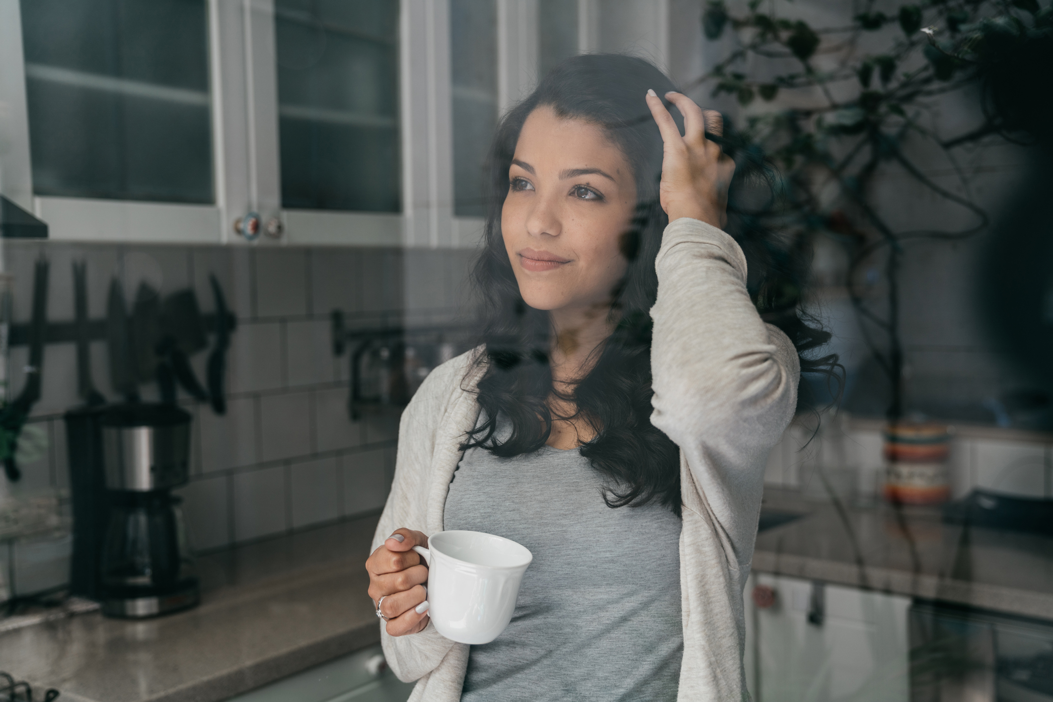 Young adult woman is drinking a coffee and looking through window