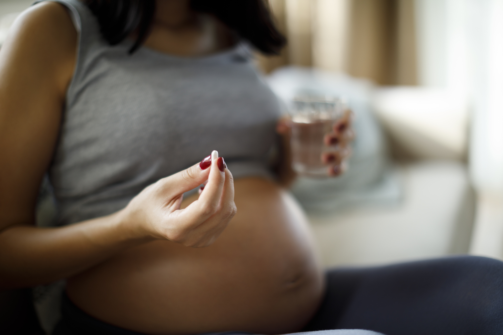 Pregnant woman taking pill at home