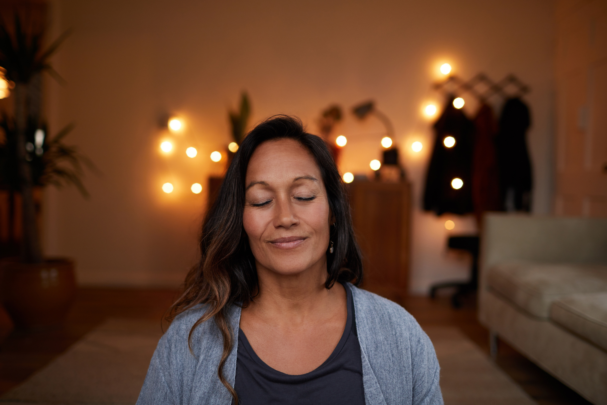 Serene mature woman smiling while meditating at home