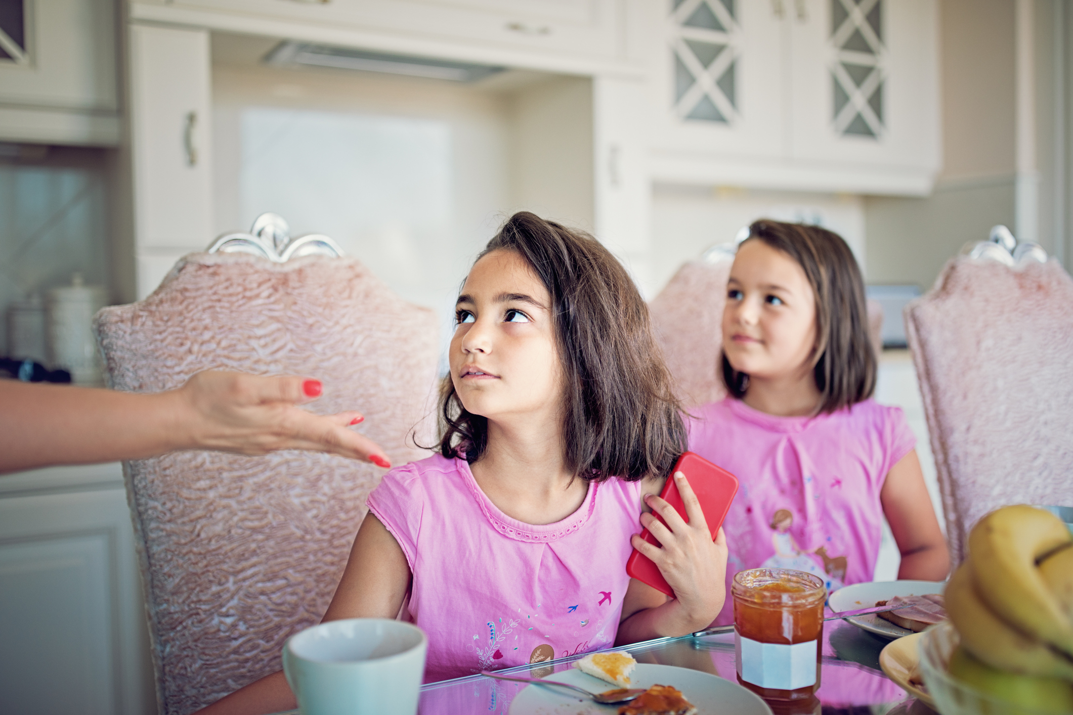 Little girl is refusing to give mobile phone to her mother at the breakfast