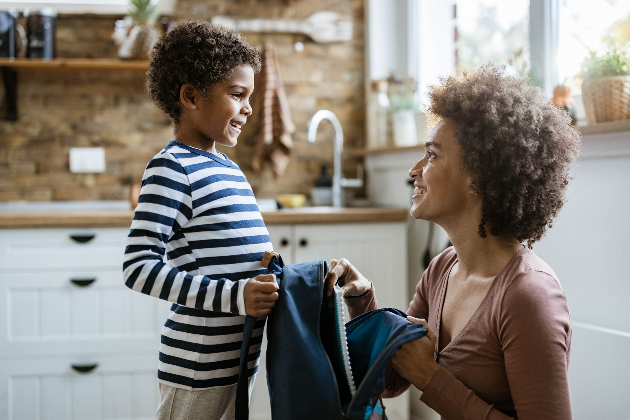 Single black mother packing her small son for school.