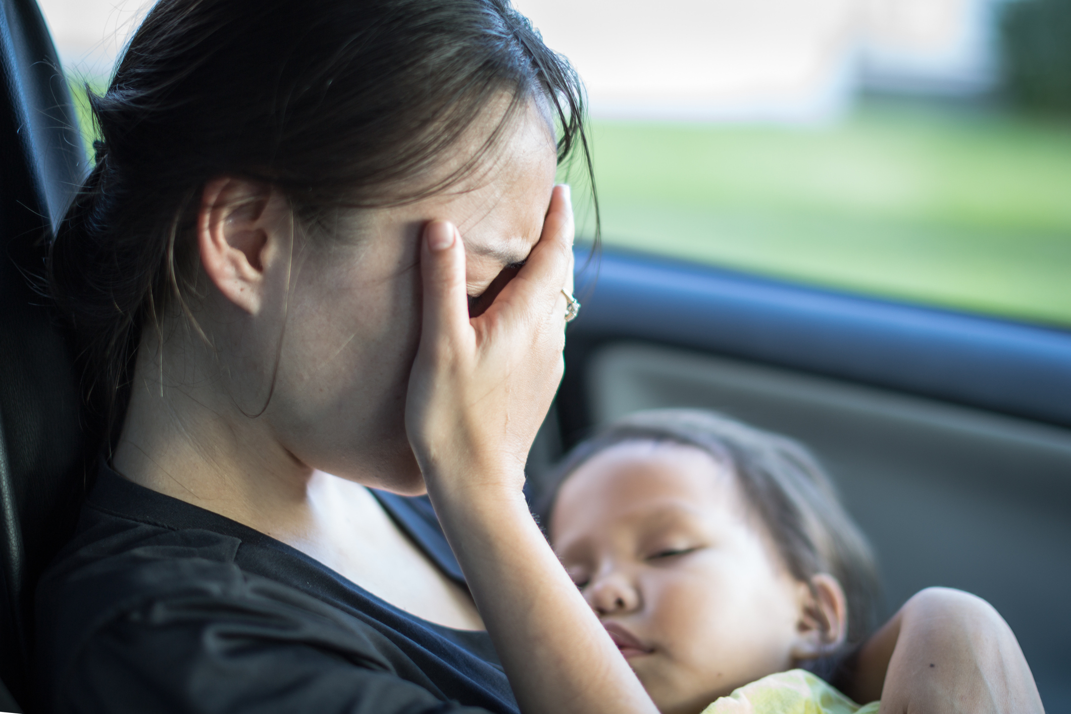 Stressed tired mother suffering from postpartum depression, holding her baby.