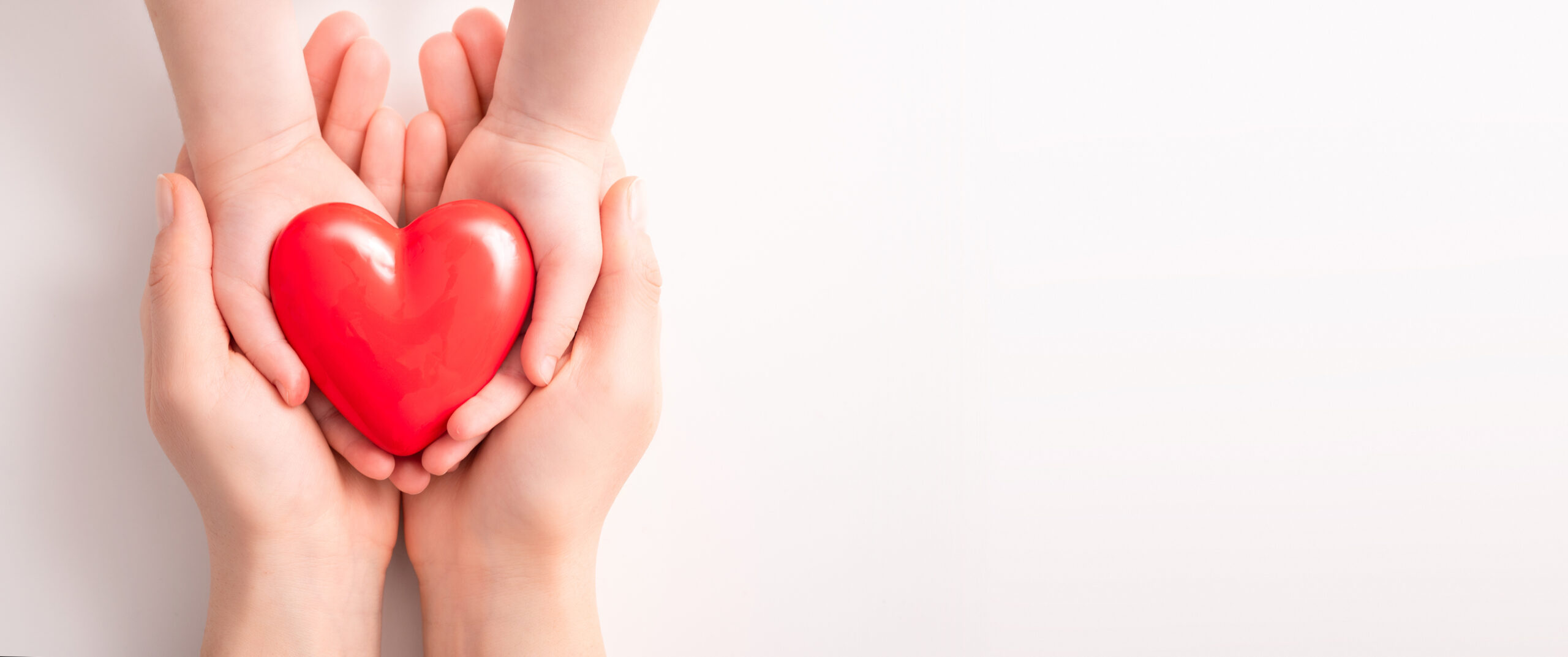 The adult and the child holding red heart.