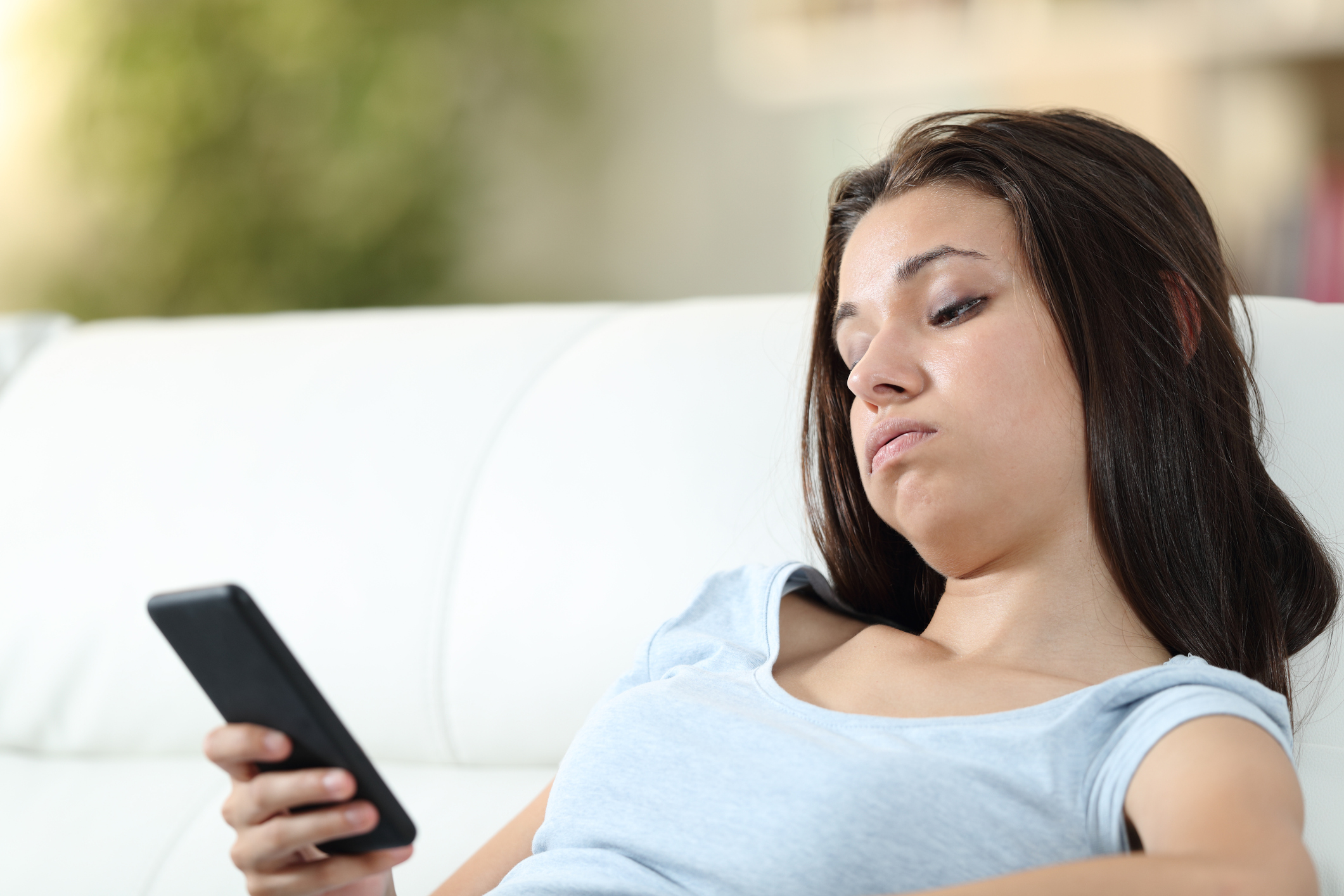 Bored girl checking mobile phone at home