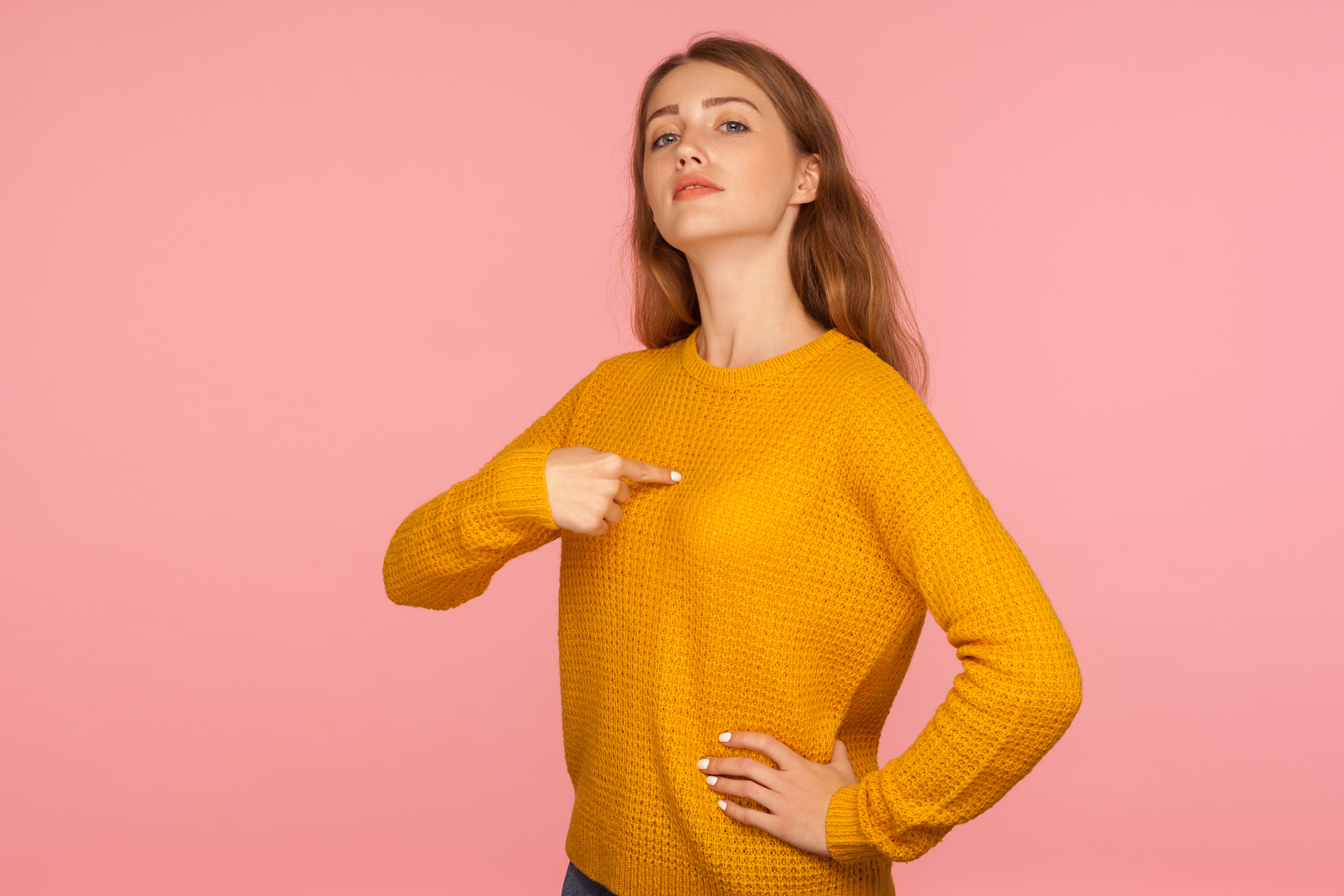 This is me! Portrait of attractive haughty ginger girl in sweater pointing at herself and looking at camera with arrogance