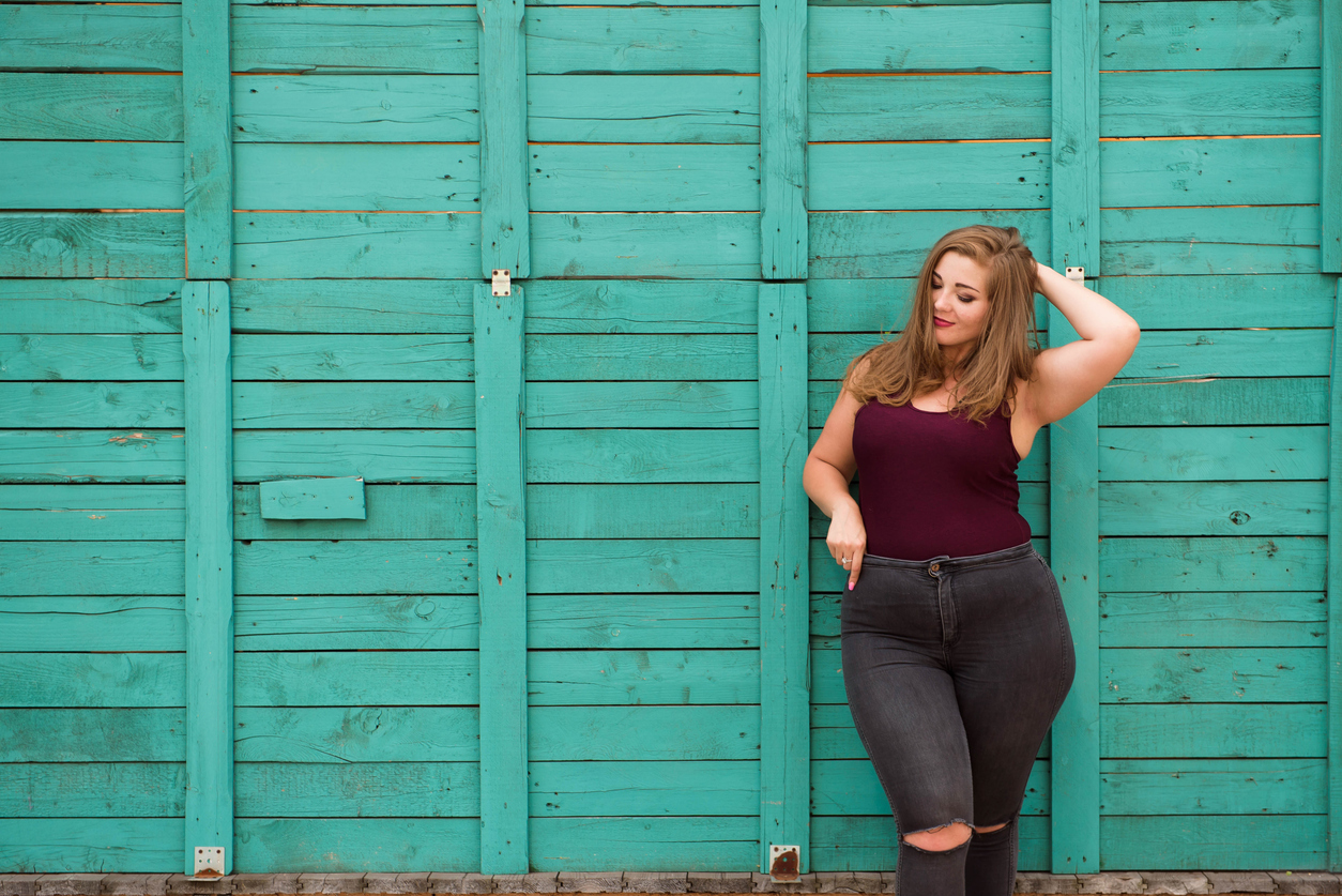 Young stylish woman walking in the city street. Spring fashion outfit, elegant look. Plus size model.