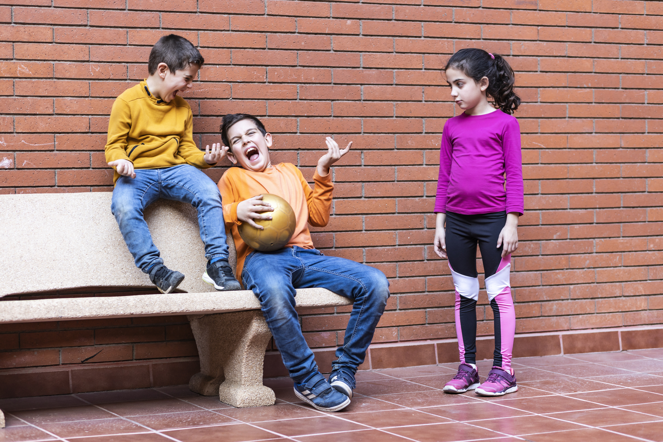 Two boys making fun of a girl because she wants to play football