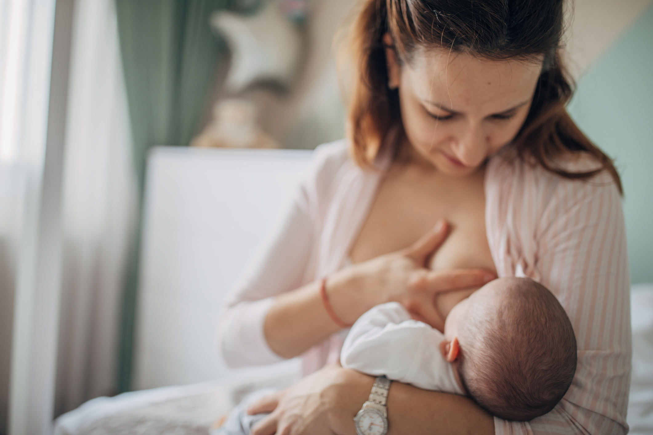 Mother breastfeeding her baby boy at home