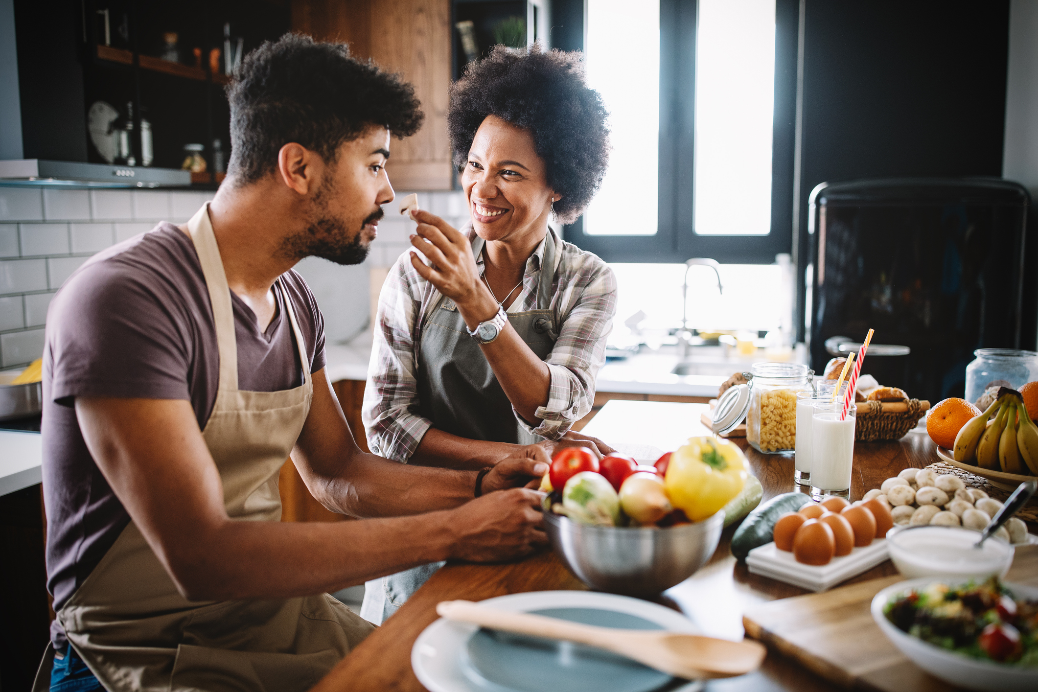 Beautiful young couple having fun and laughing while cooking in kitchen