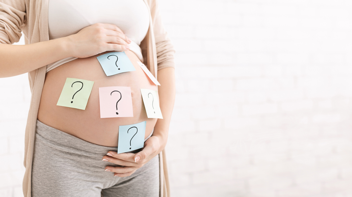 Pregnant woman with question marks on paper stickers on tummy