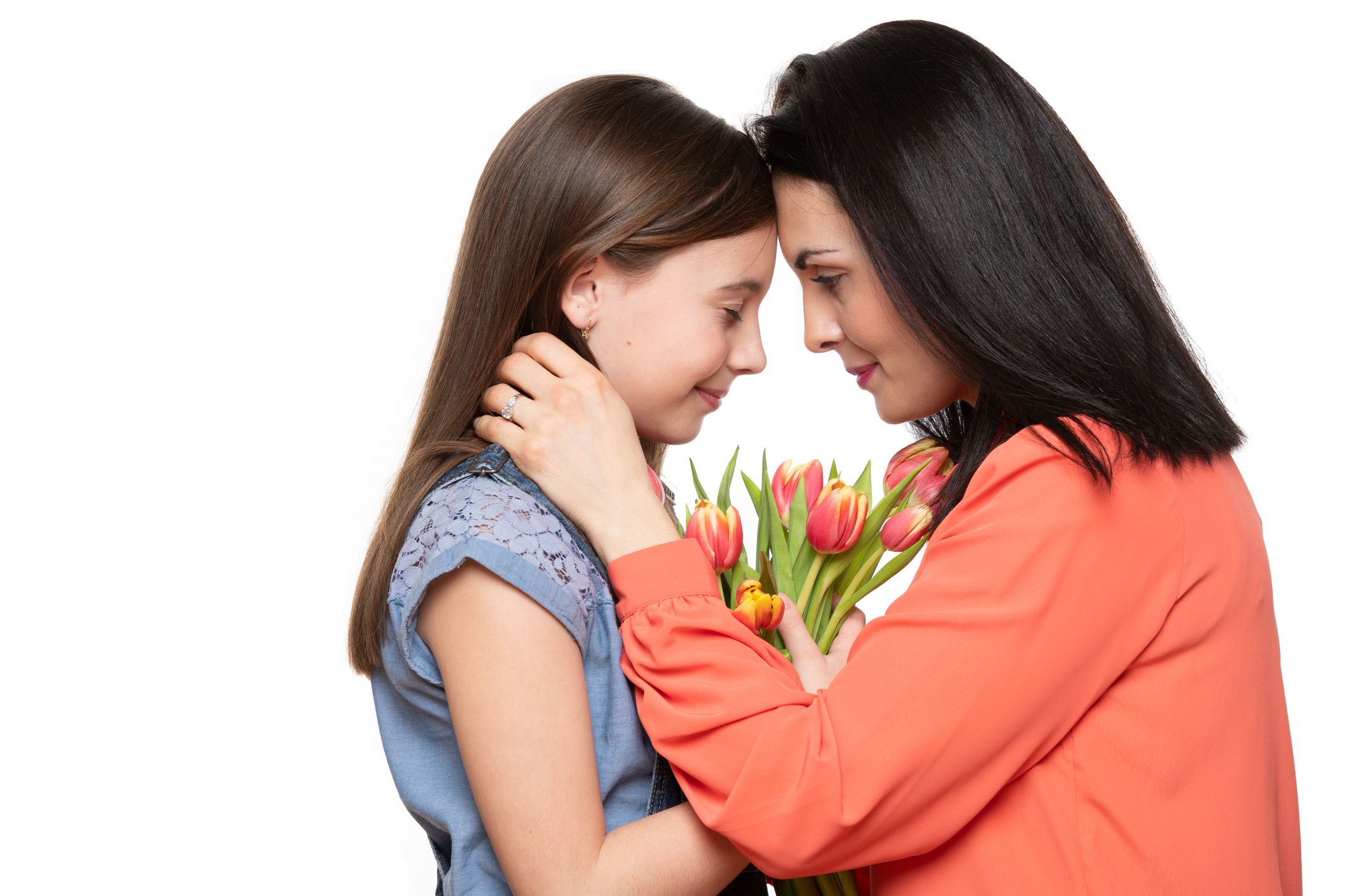 Happy Mother's Day, Women's day or Birthday background. Adorable girl giving mom bouquet of pink tulips. Studio portrait of a loving mother embracing her daughter on white background.