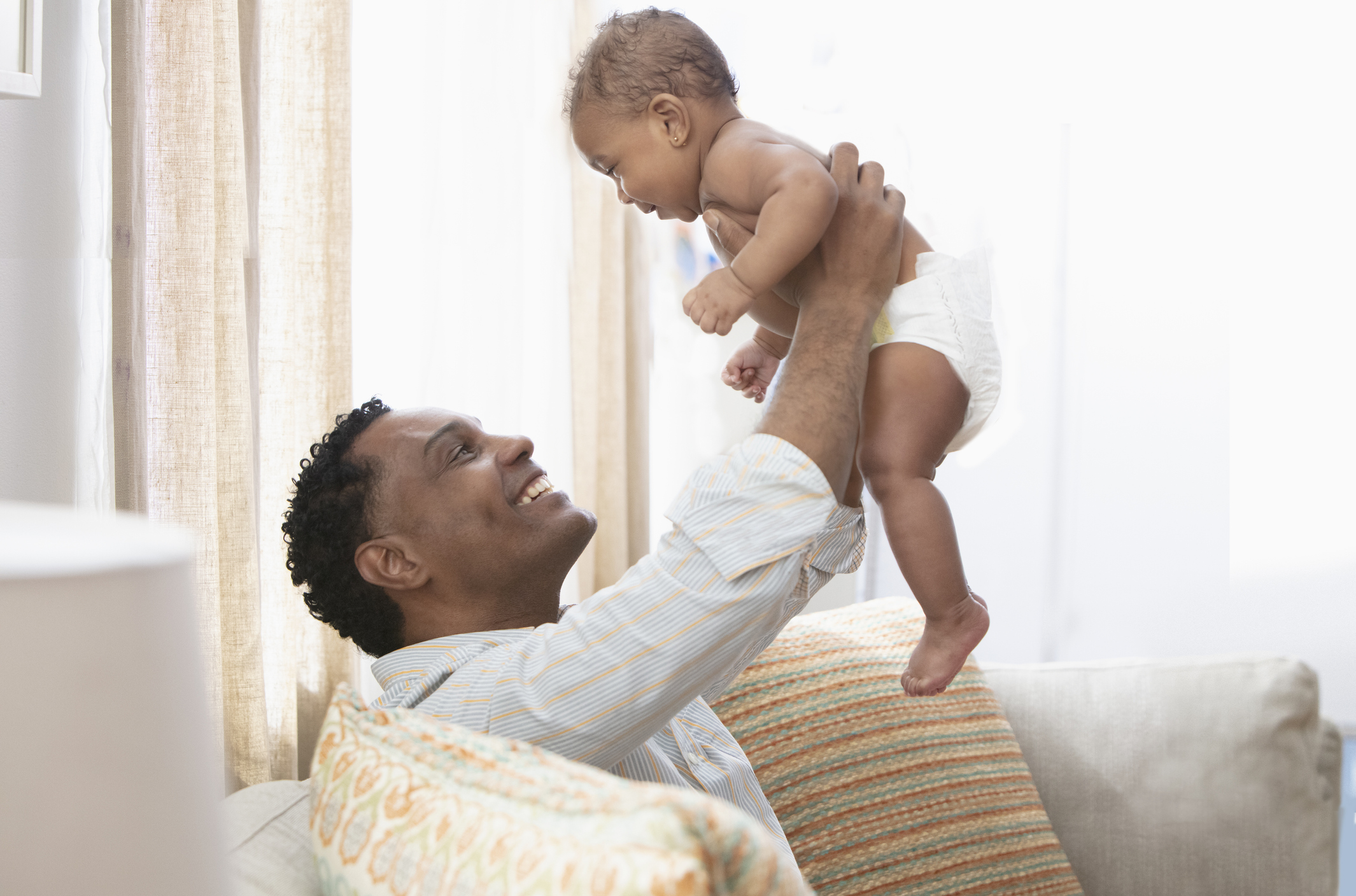 Father lifting up his daughter in living room