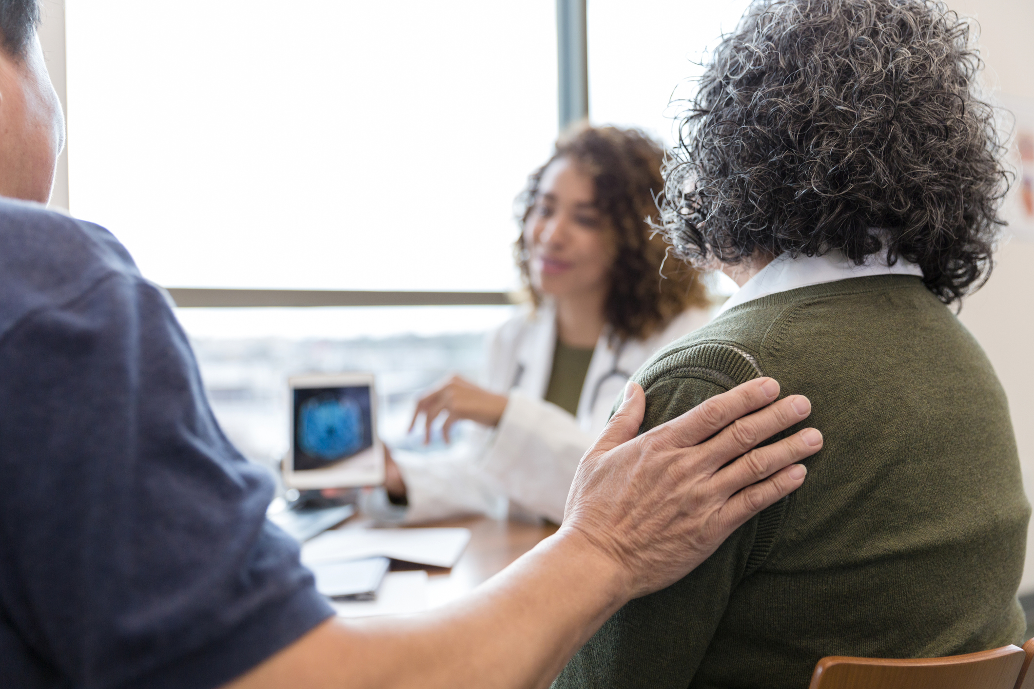 Husband comforts wife during appointment with a neurologist
