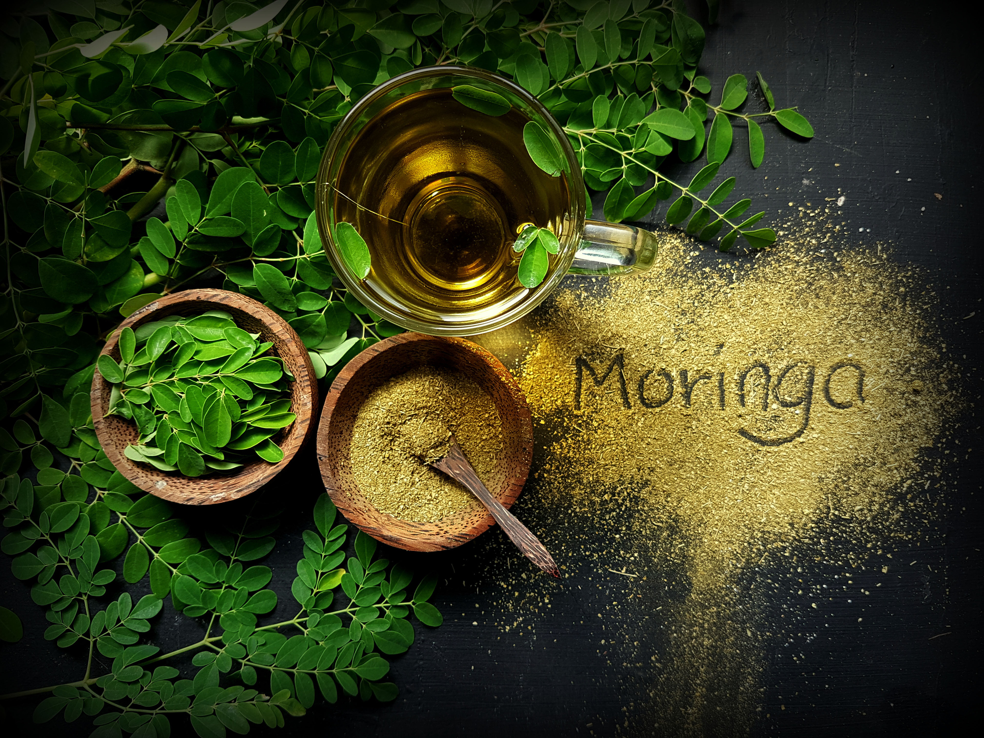 Moringa Oleifera tea with powder on table written moringa wording