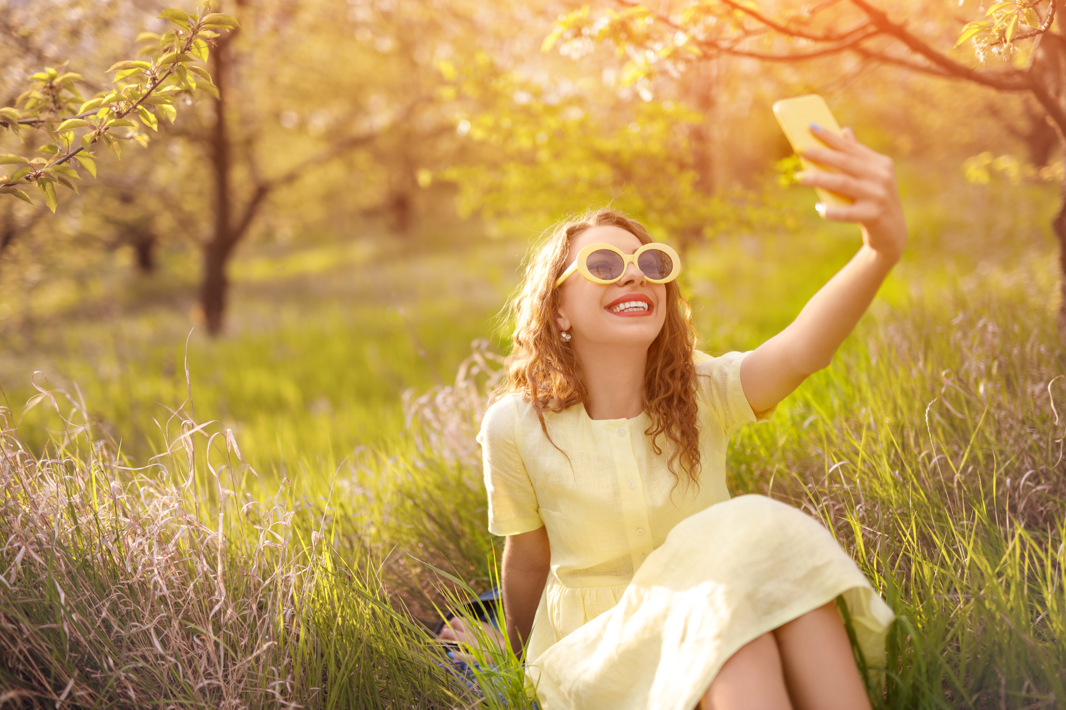 Joyful modern woman taking selfie while relaxing on grass