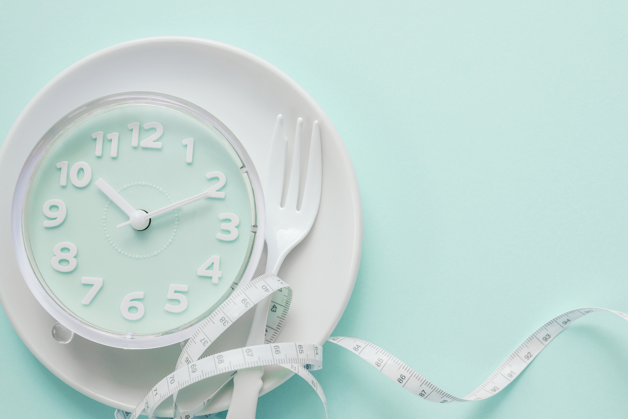 Blue clock on white plate, Intermittent fasting concept, ketogenic diet, weight loss, skip meal