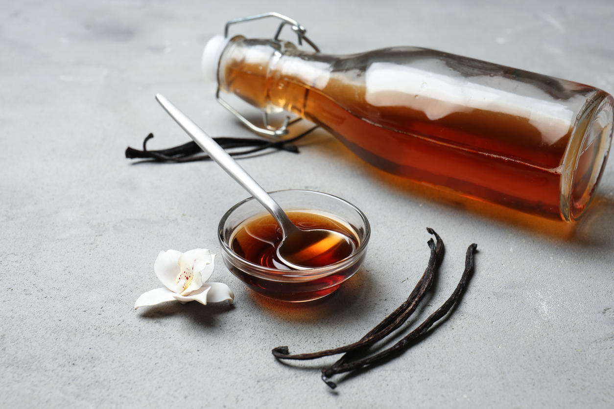 Glass bowl and bottle with vanilla extract on table