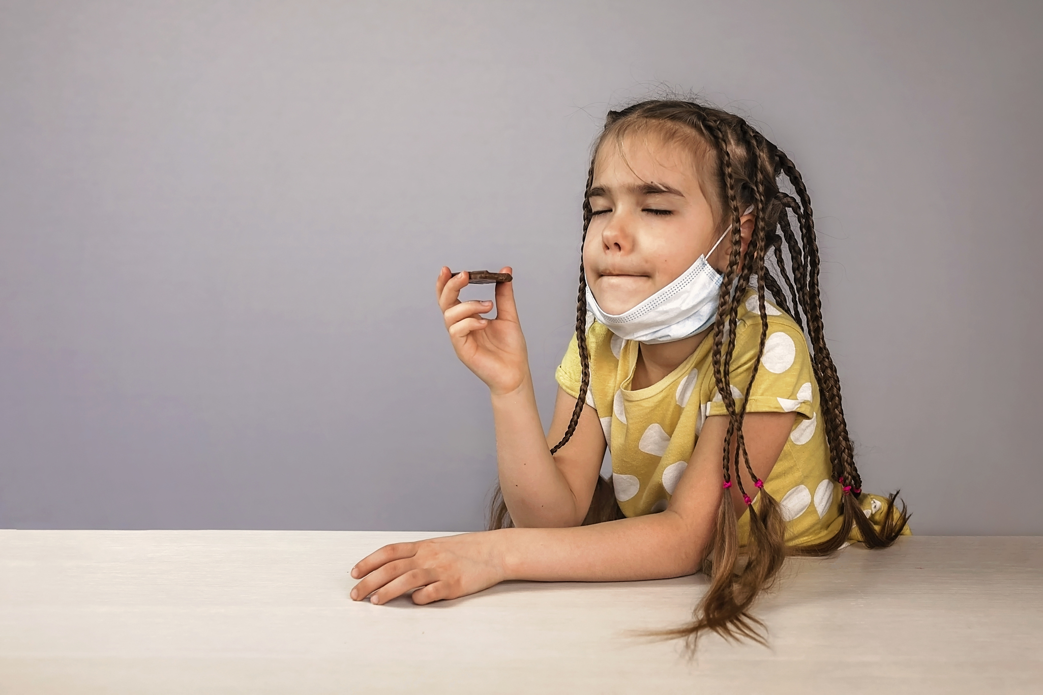 Girl wearing off her medicine respirator mask and eating chocolate bars with pleasure