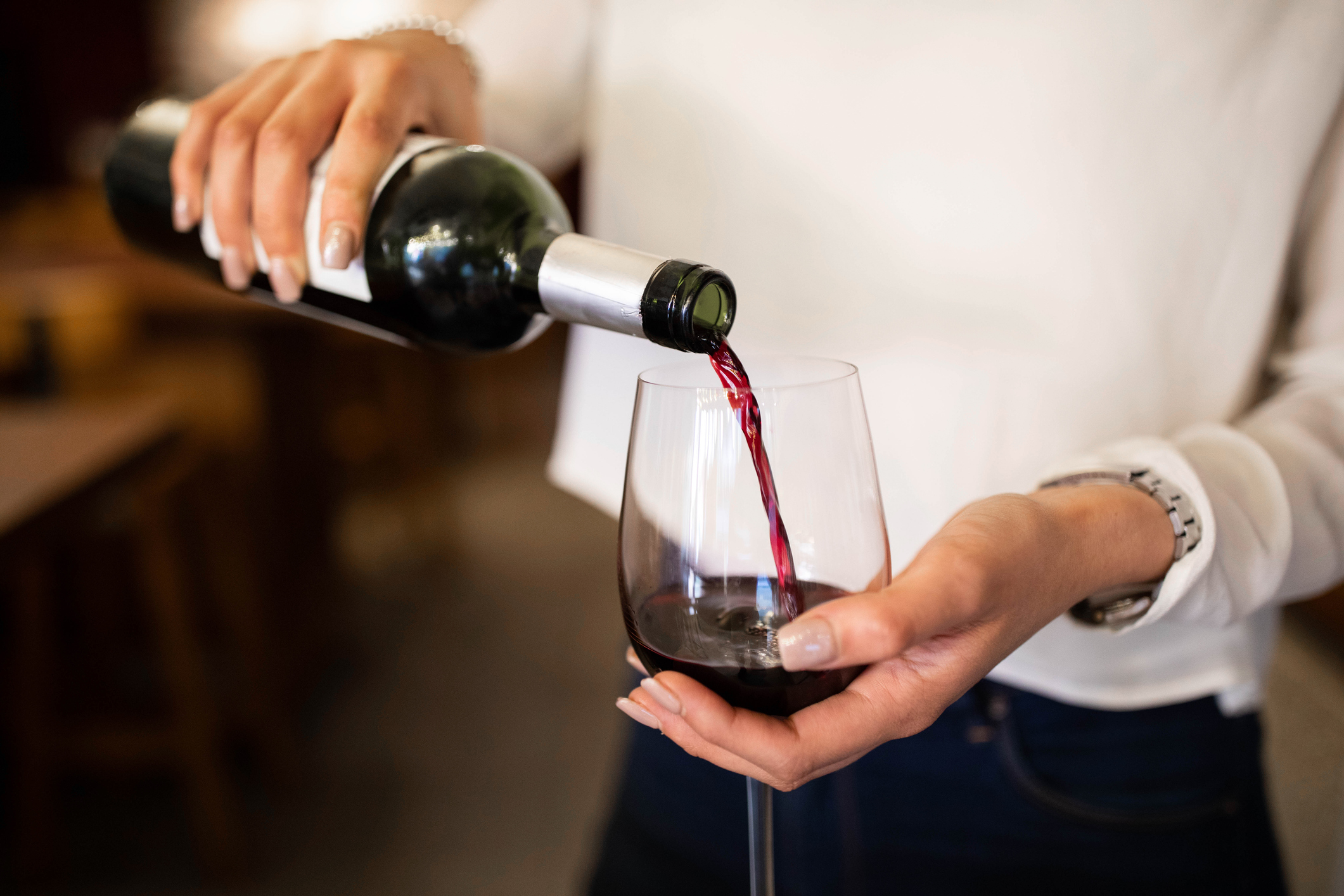 Woman serving red wine in a winery