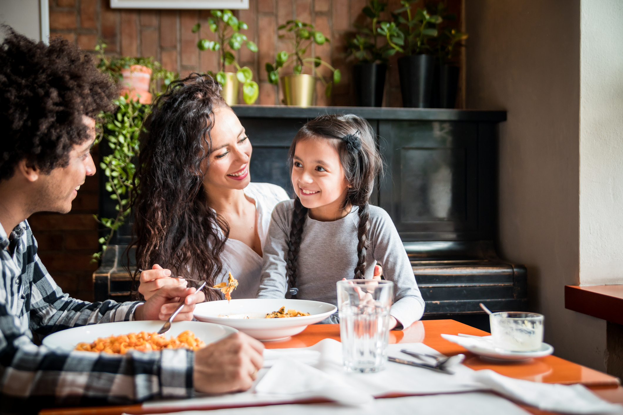 Happy african american family eating lunch together at restaurant and having fun