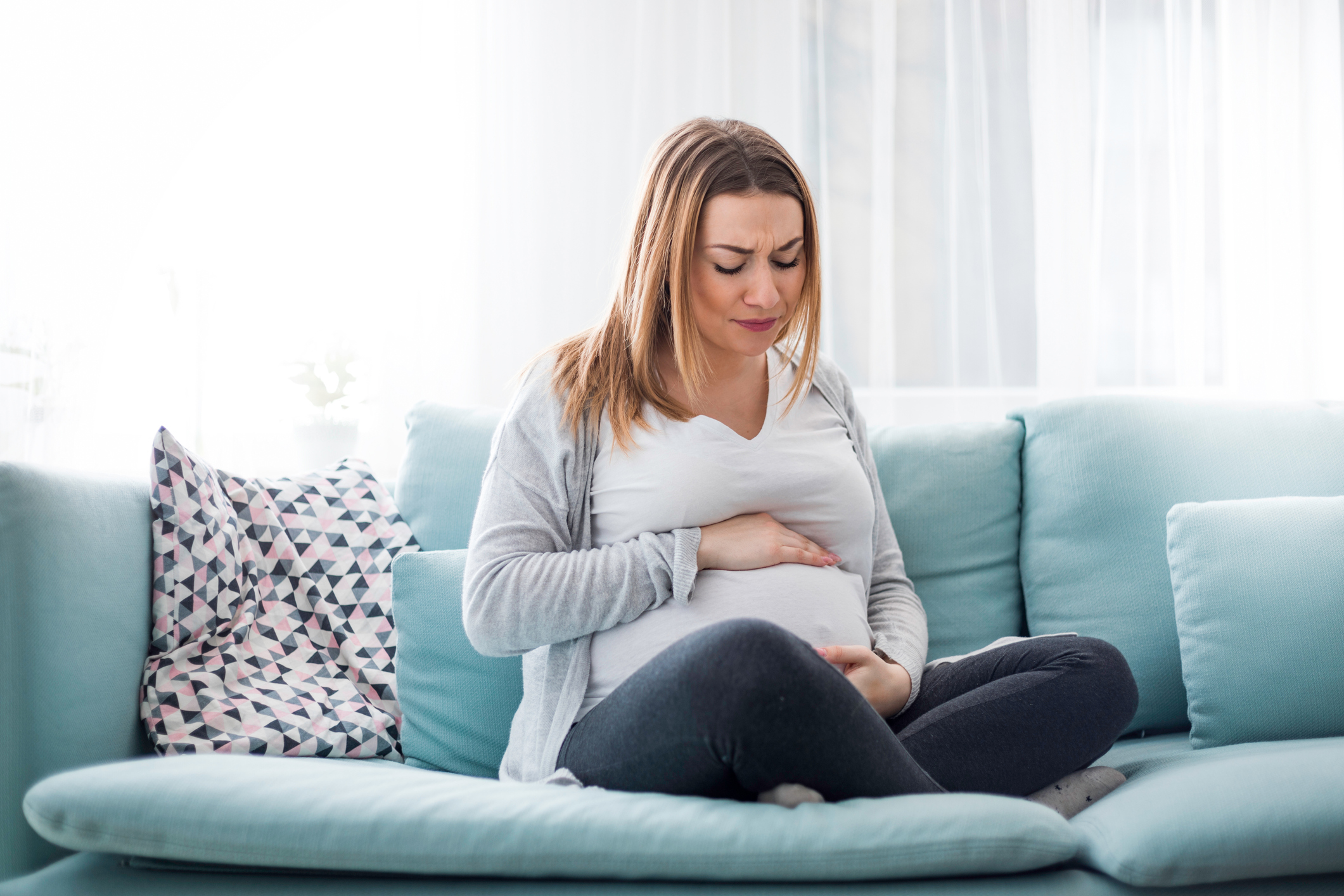 Young pregnant woman suffering from abdominal pain at home