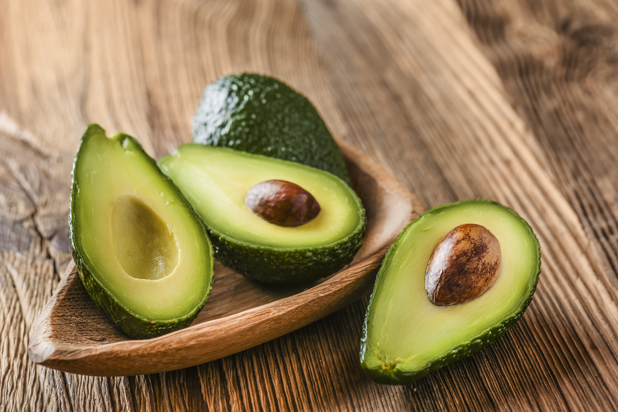 Avocado on old wooden table in bowl.