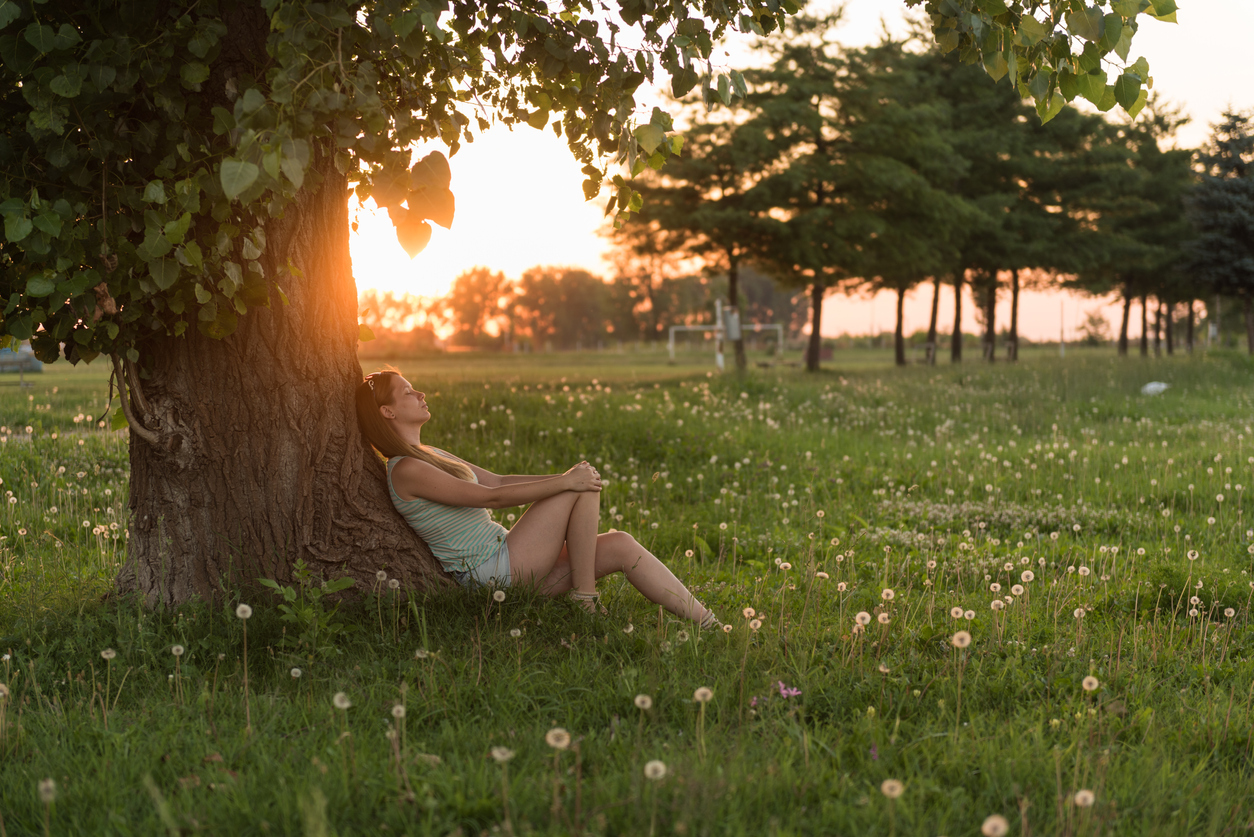 Young woman enjoying sunset under the tree