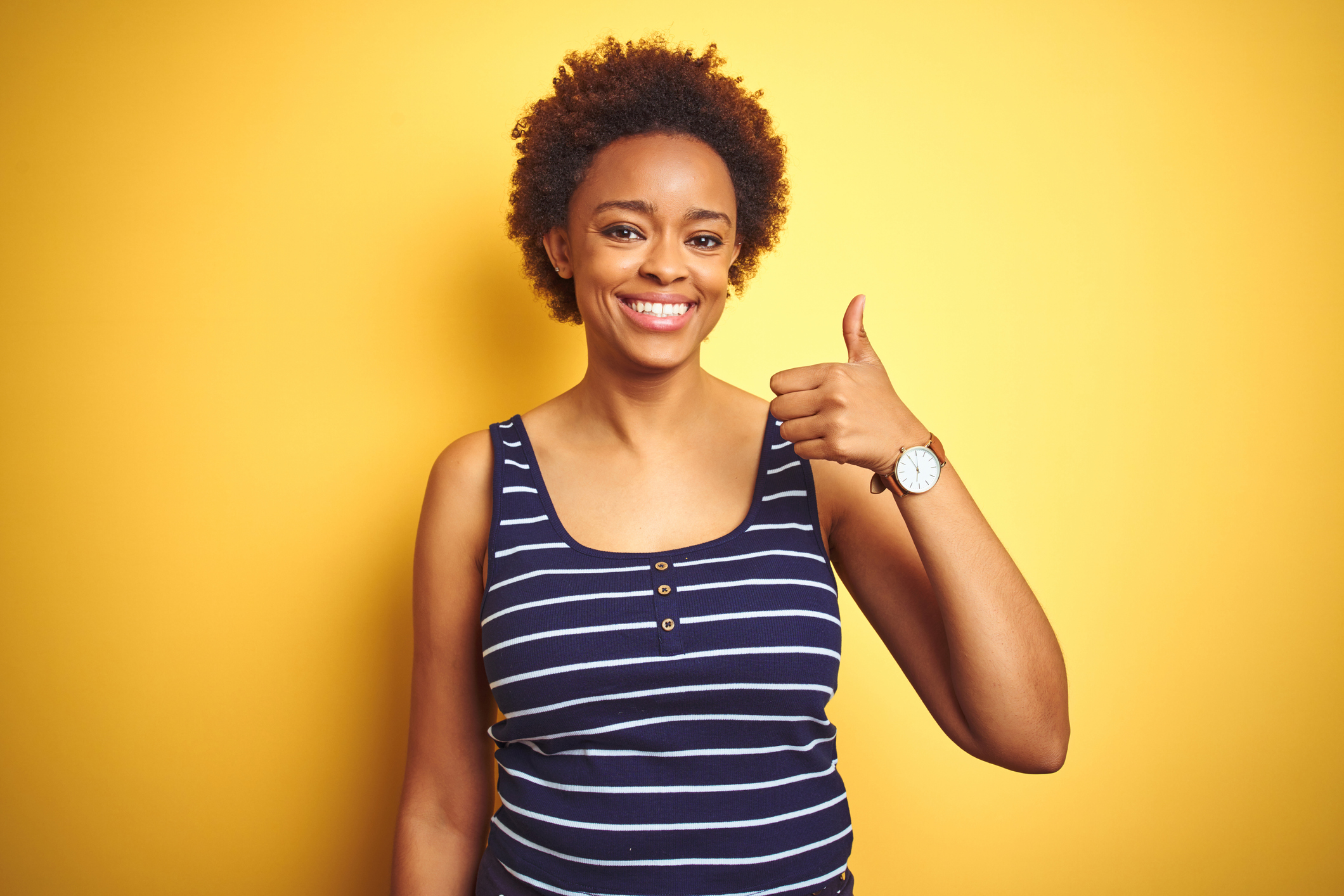 Beauitul african american woman wearing summer t-shirt over isolated yellow background doing happy thumbs up gesture with hand. Approving expression looking at the camera showing success.